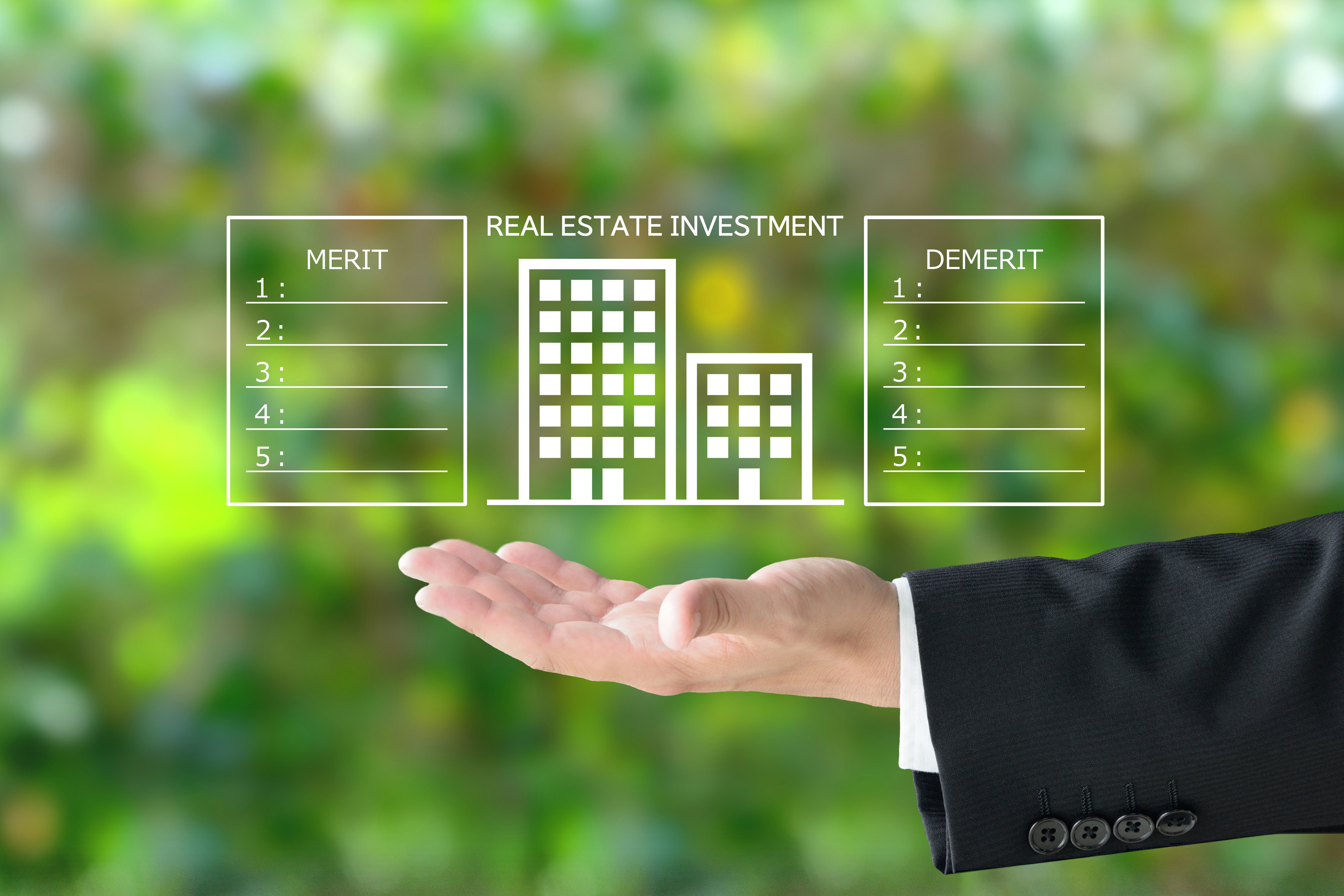 Business man's hand and building pictogram and REAL ESTATE INVESTMENT word with merit and demerit lists
