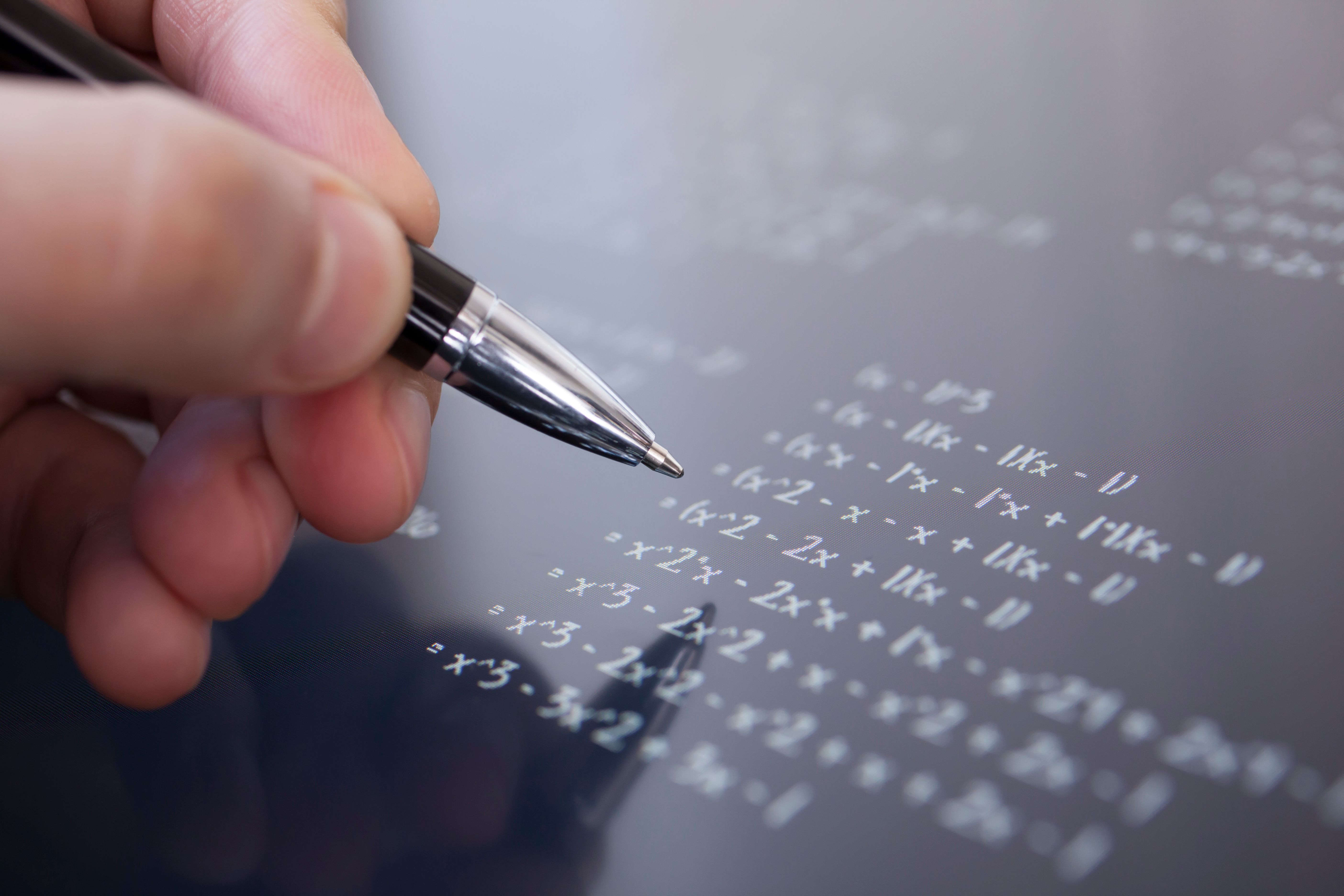 Person solving a math problem using a pen