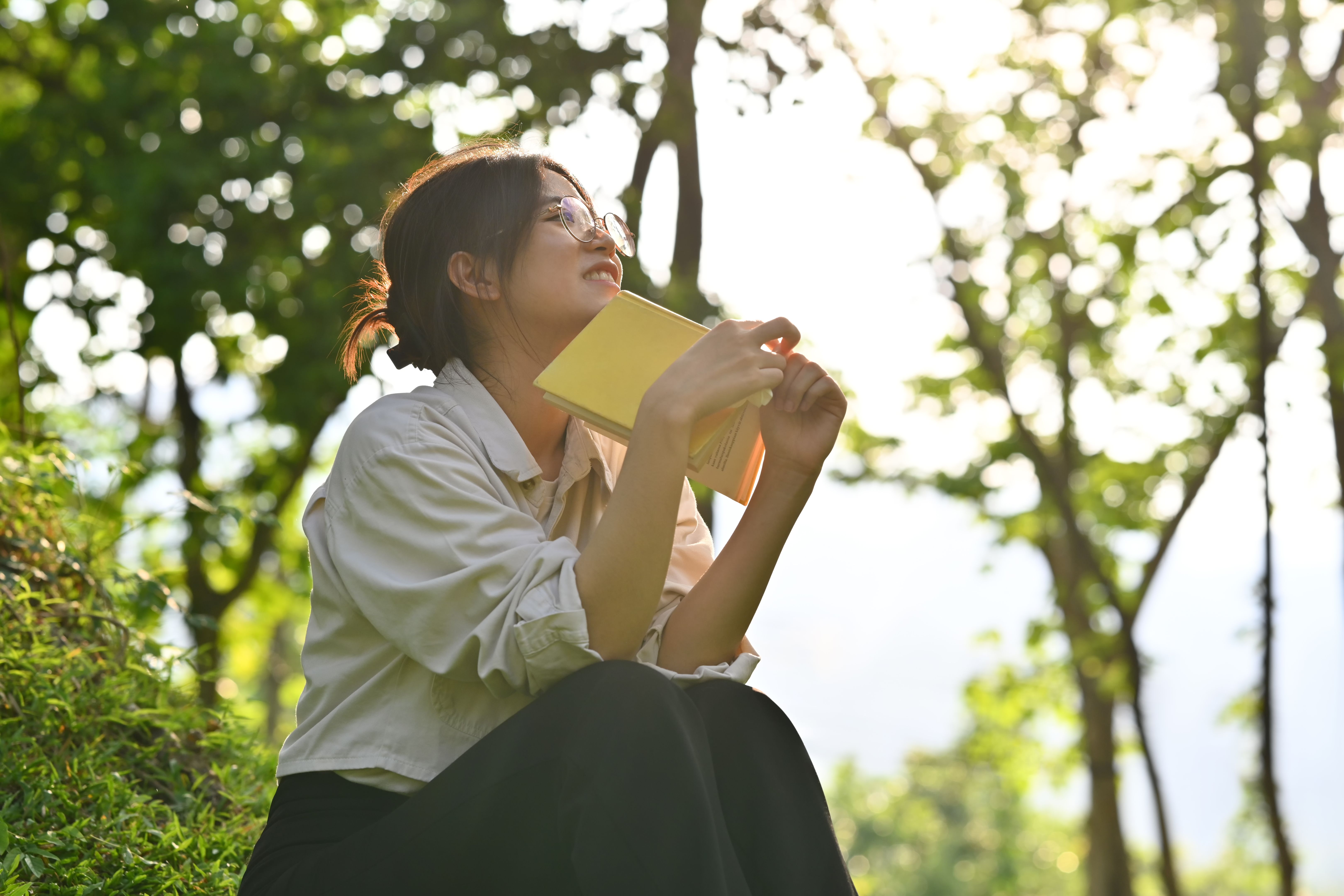 Relaxed young woman reading book on a green meadow in beautiful summer day. Education, learning and lifestyle. Relaxed young woman reading book on a green meadow in beautiful summer day. Education, learning and lifestyle.