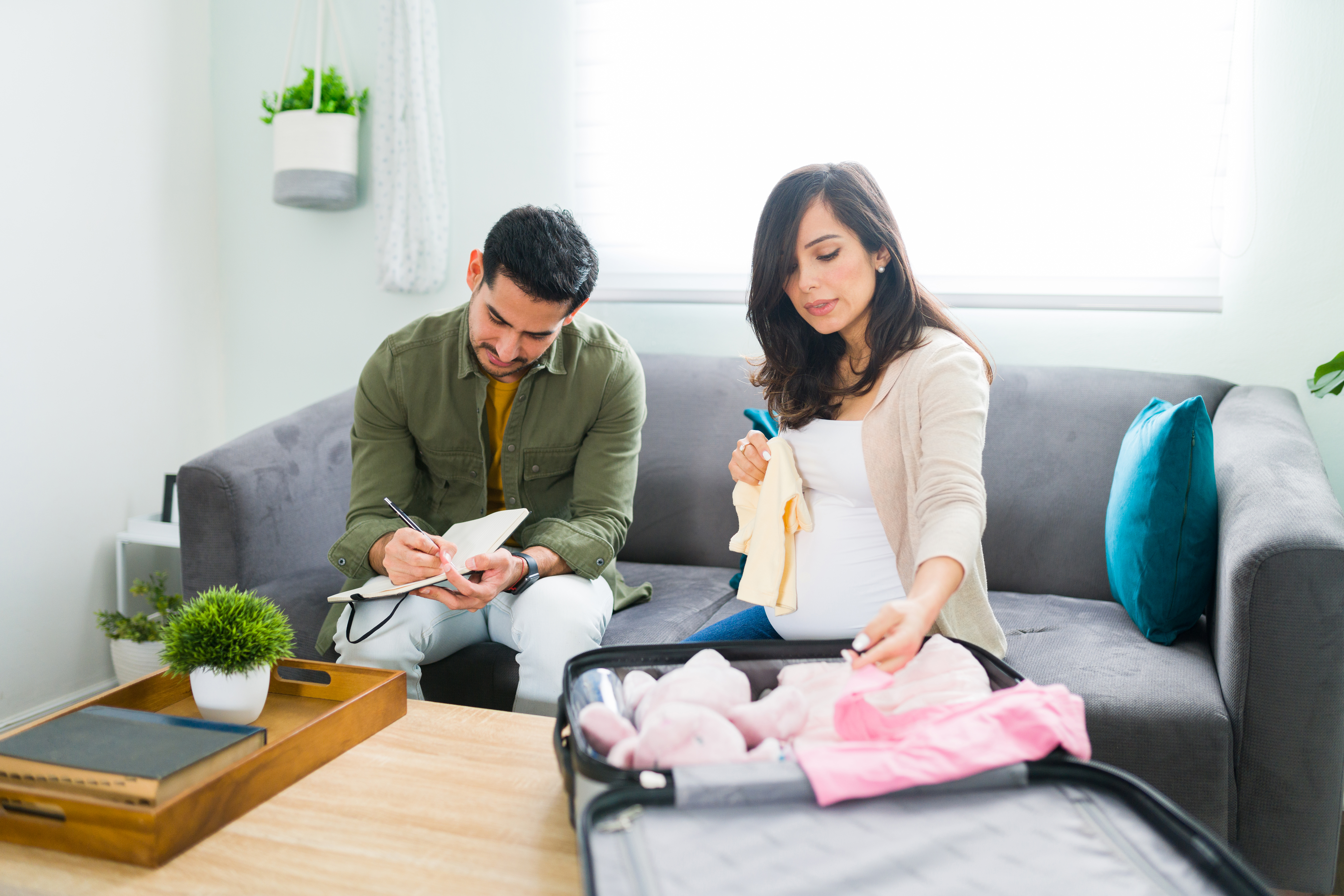 Handsome husband and pregnant wife packing a hospital suitcase Handsome husband and pregnant wife packing a hospital suitcase