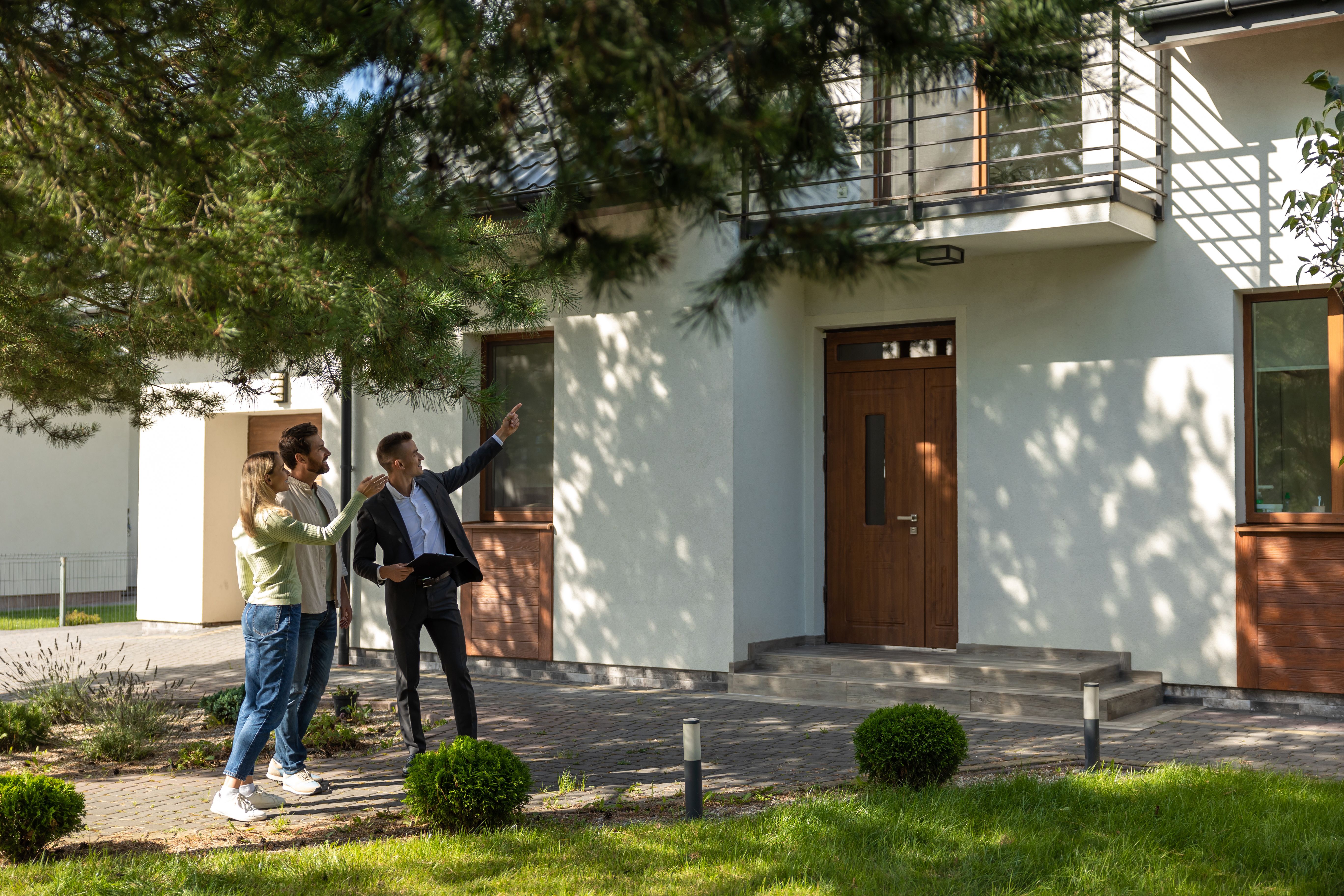 Agent showing house entrance to clients in suburban setting
