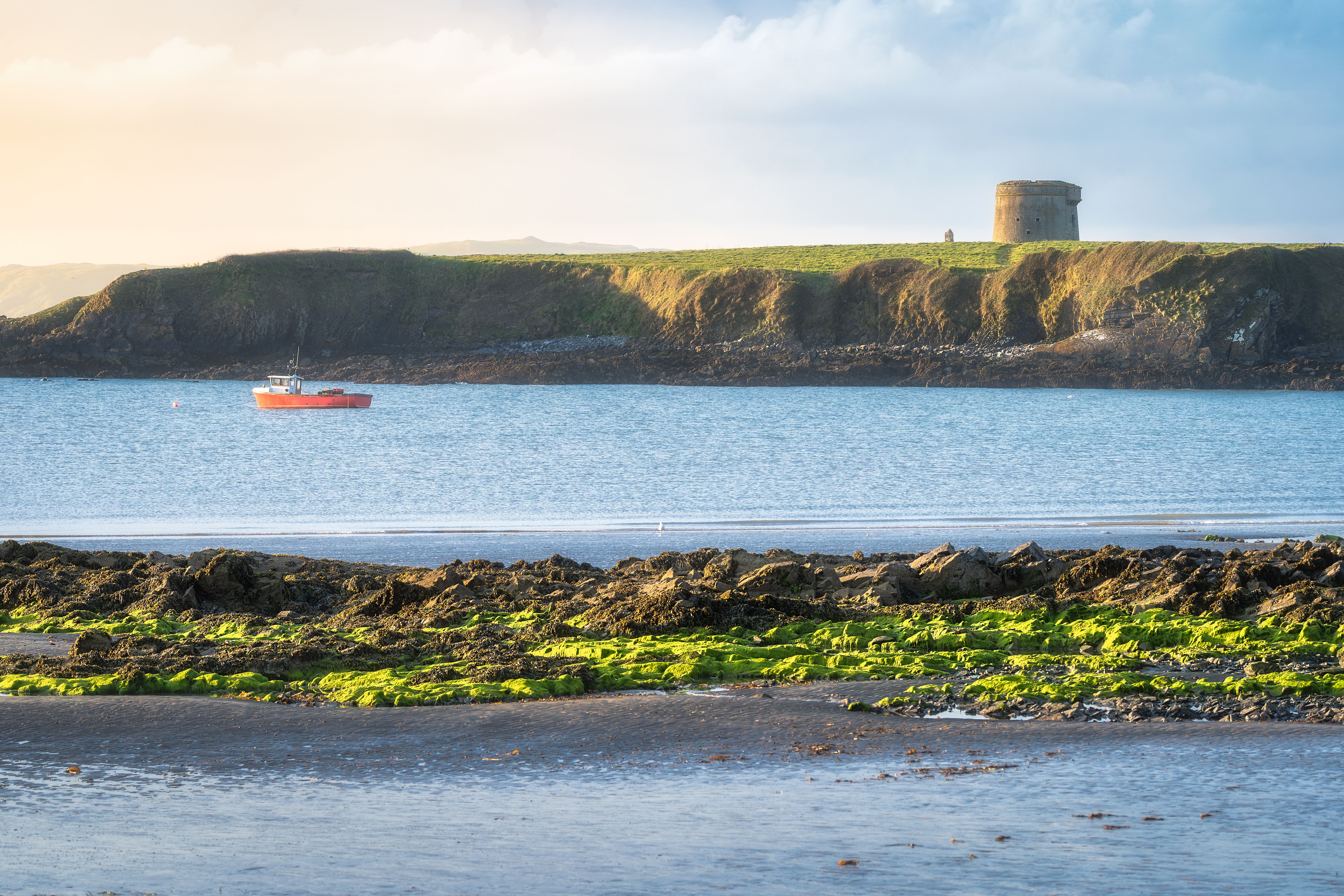 A peaceful and picturesque calm seascape featuring a historic tower alongside a vibrant green seaweedfilled coastline A peaceful and picturesque calm seascape featuring a historic tower alongside a vibrant green seaweedfilled coastline