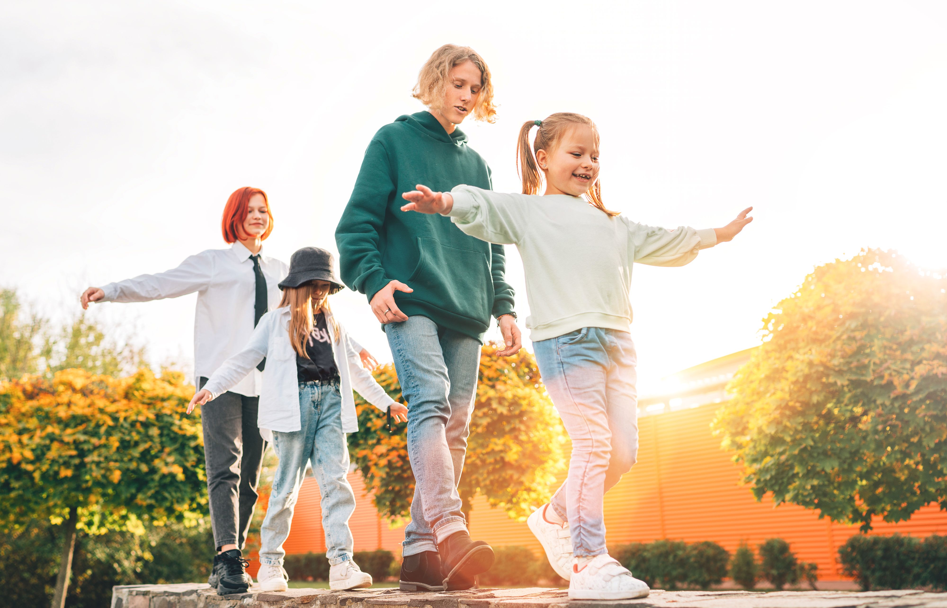 Smiling teenager boy and a laughing sisters girls kids walking in row in the autumnal sunny city park.Careless young teenhood time and a outdoor time spending concept image. Smiling teenager boy and a laughing sisters girls kids walking in row in the autumnal sunny city park.Careless young teenhood time and a outdoor time spending concept image.