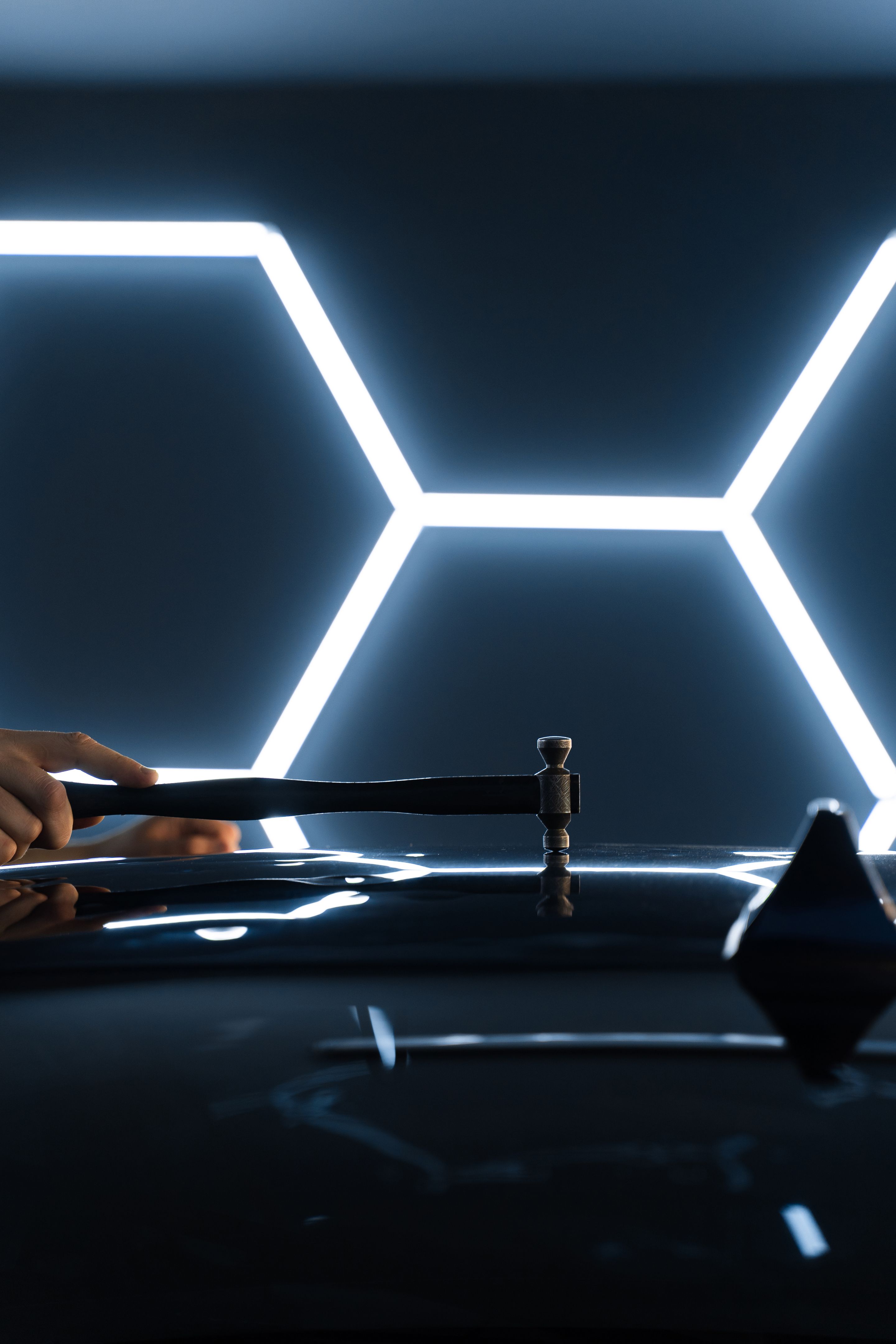 Bei der lackfreien Dellenreparatur PDR werden Dellen unter Lichtreflexion klopfen, um Präzision zu erzielen. Der Techniker verwendet PDR-Werkzeuge, um Dellen von der Motorhaube während der lackfreien Dellenreparatur zu entfernen.