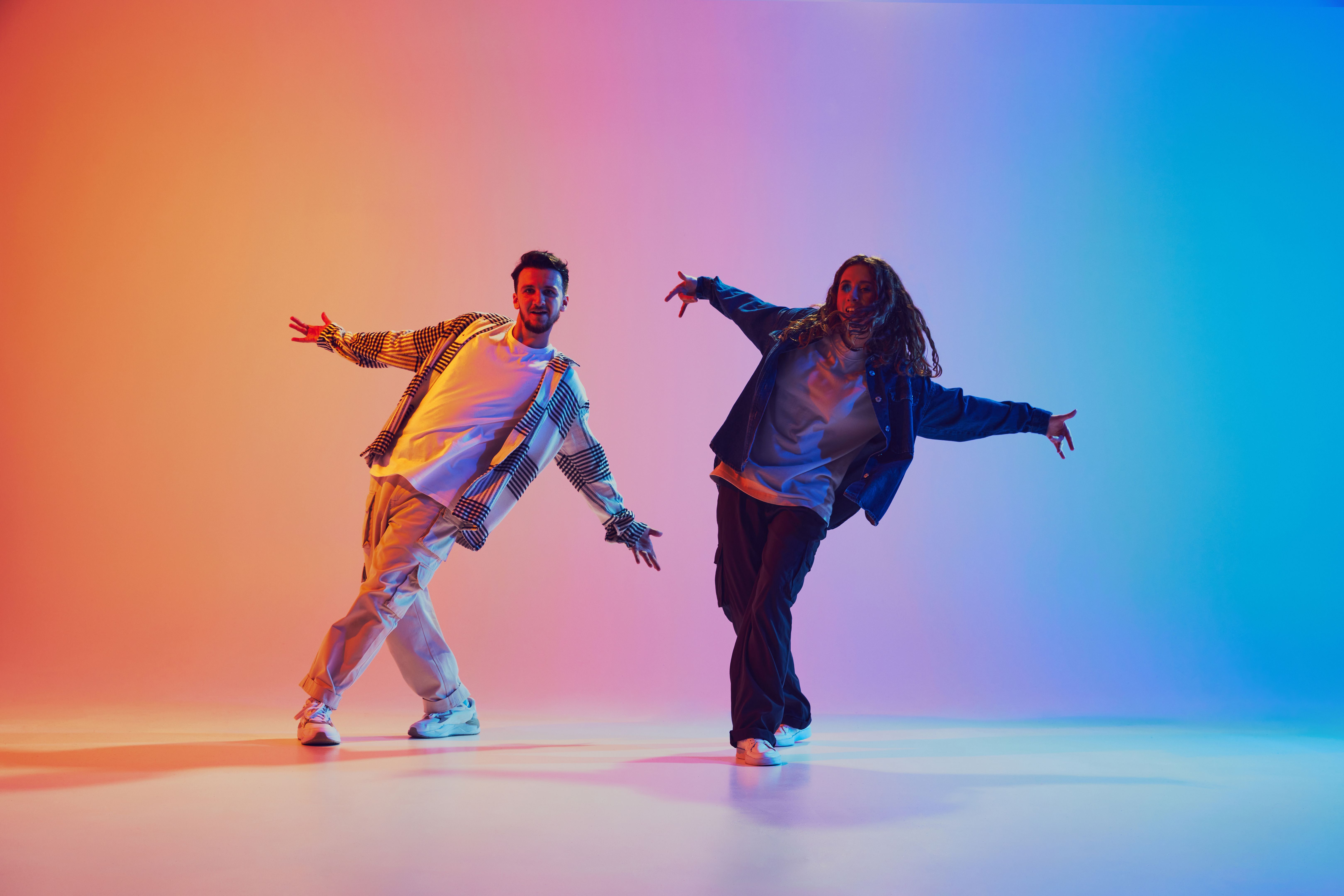 Two dancers, man and woman dancing in motion against gradient studio background. Dynamic movement. Two dancers, man and woman dancing in motion against gradient studio background. Dynamic movement.