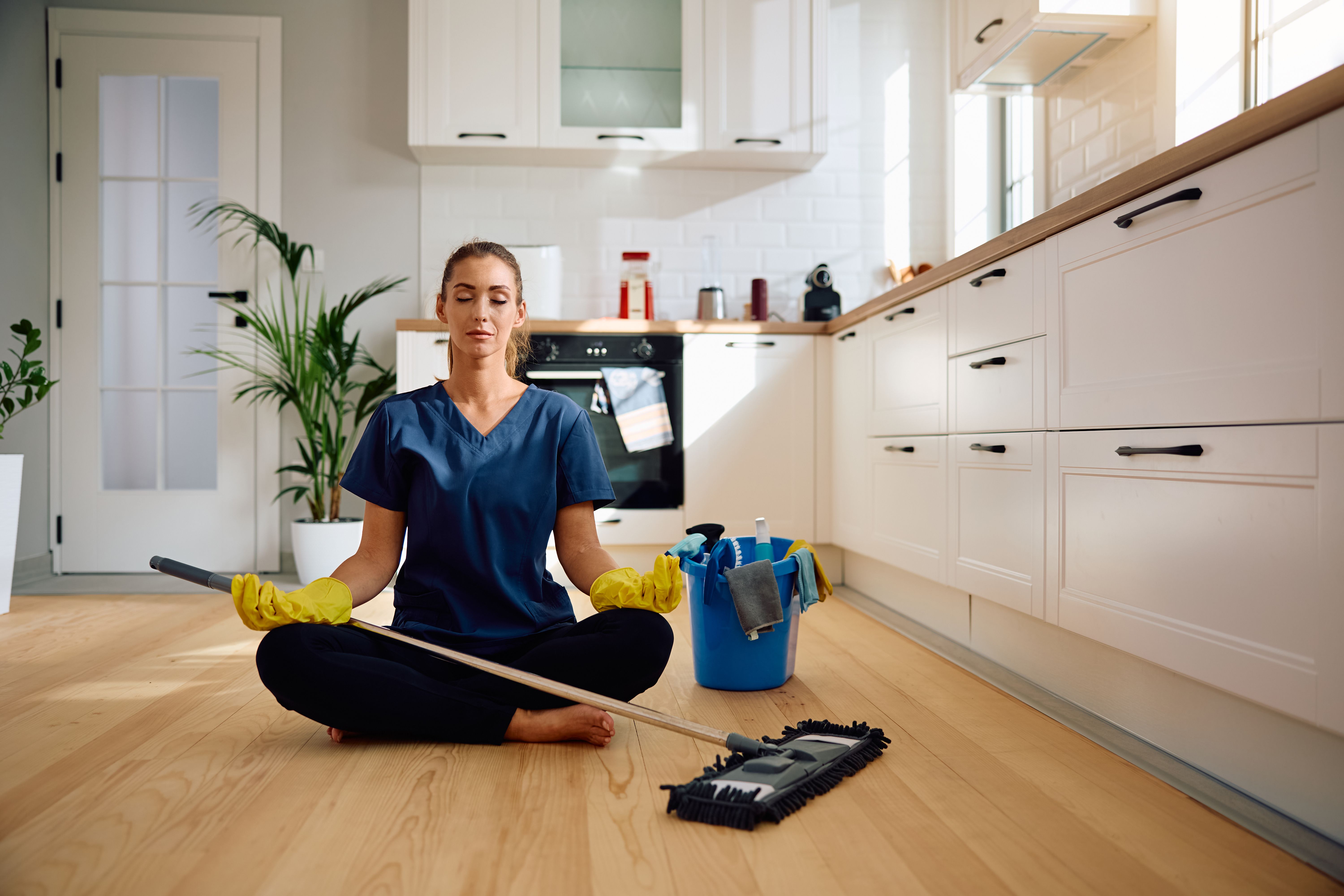 Young housekeeper meditating after cleaning the kitchen. Young housekeeper meditating after cleaning the kitchen.