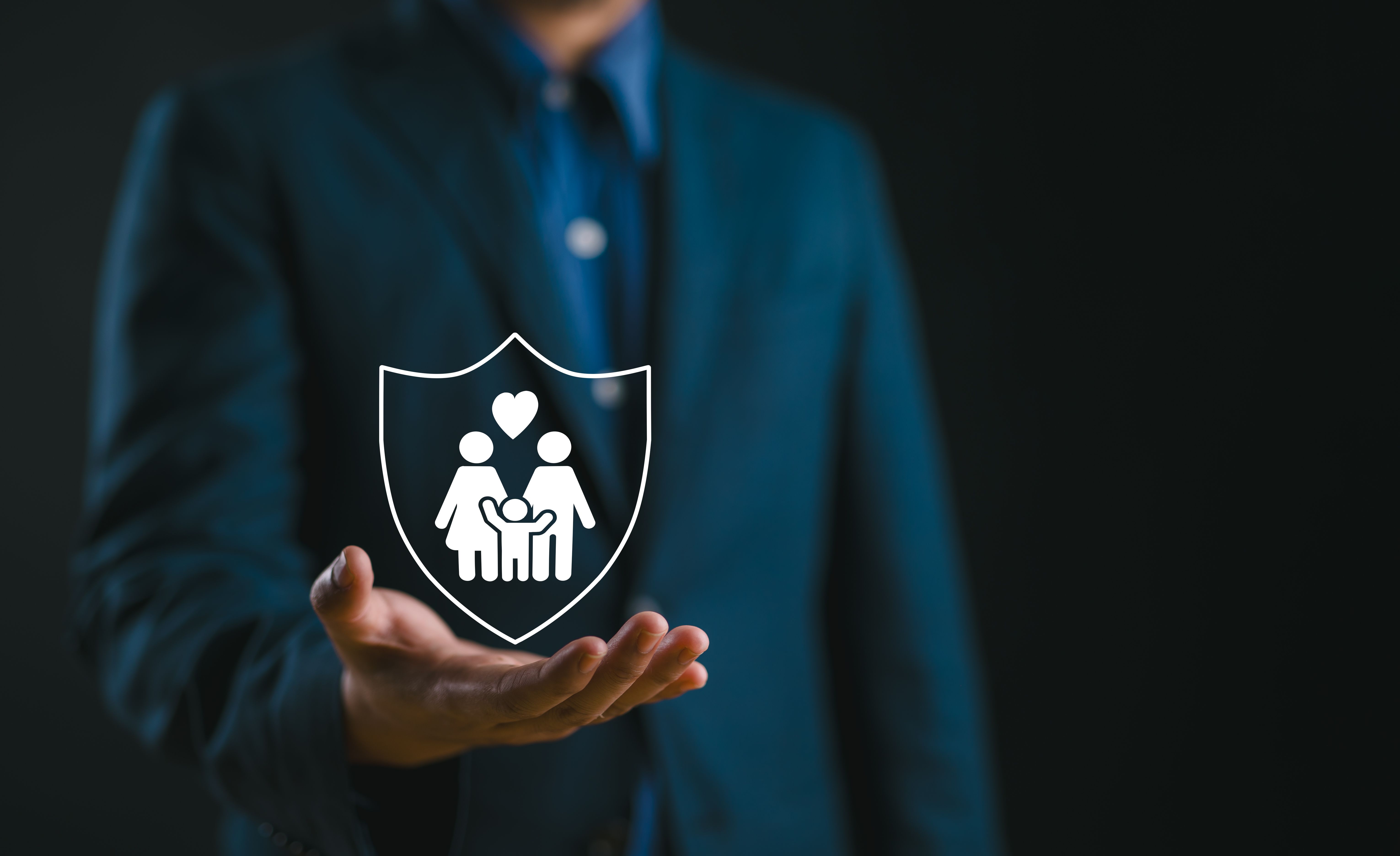 Supporting family futures, Businessman protective gesture complements young family silhouette. Health and house insurance icons symbolize protection, reinforcing family life insurance.