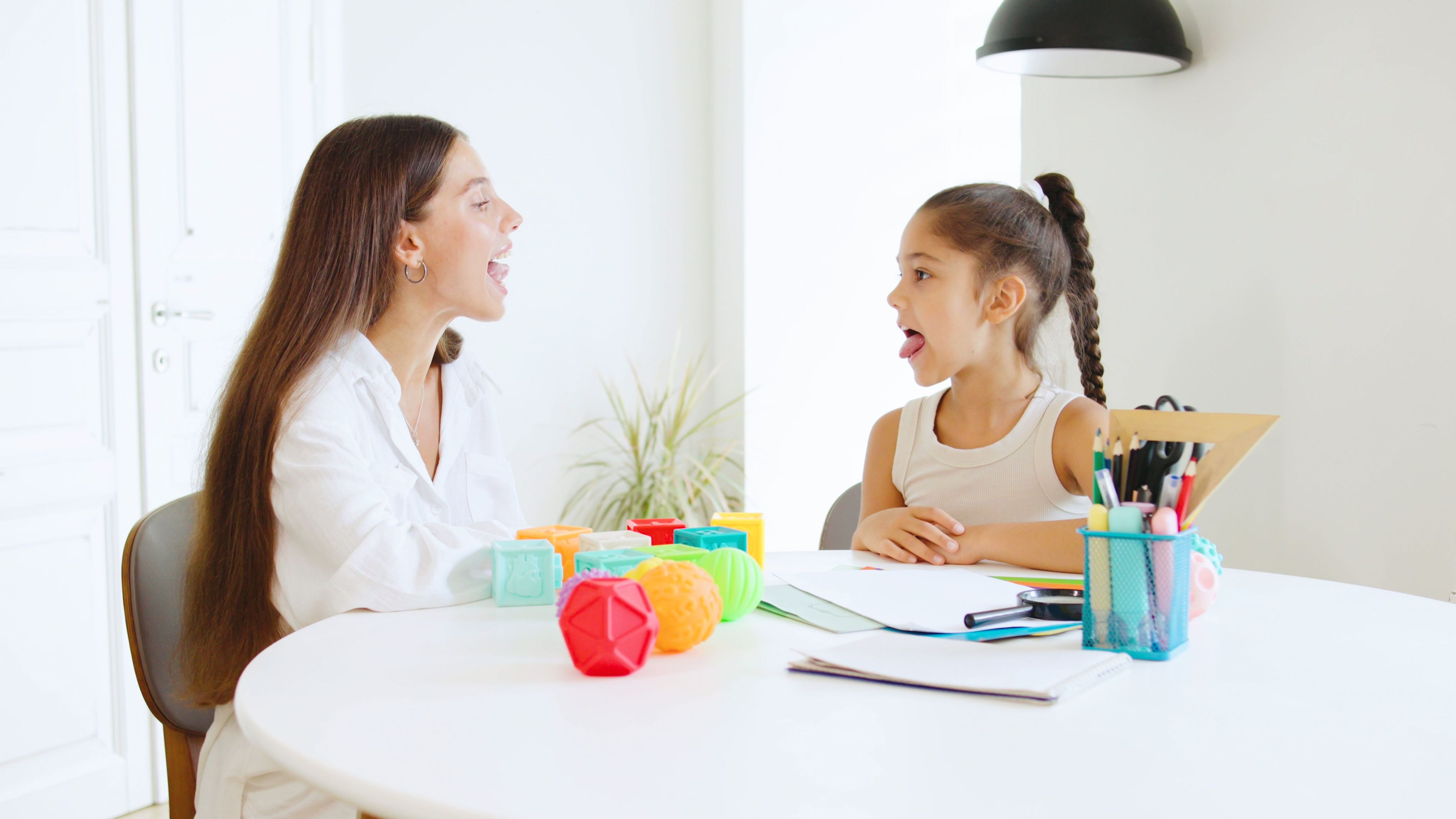 Speech therapist engages a young girl in playful language exercises at a bright, modern office during a therapy session Speech therapist engages a young girl in playful language exercises at a bright, modern office during a therapy session