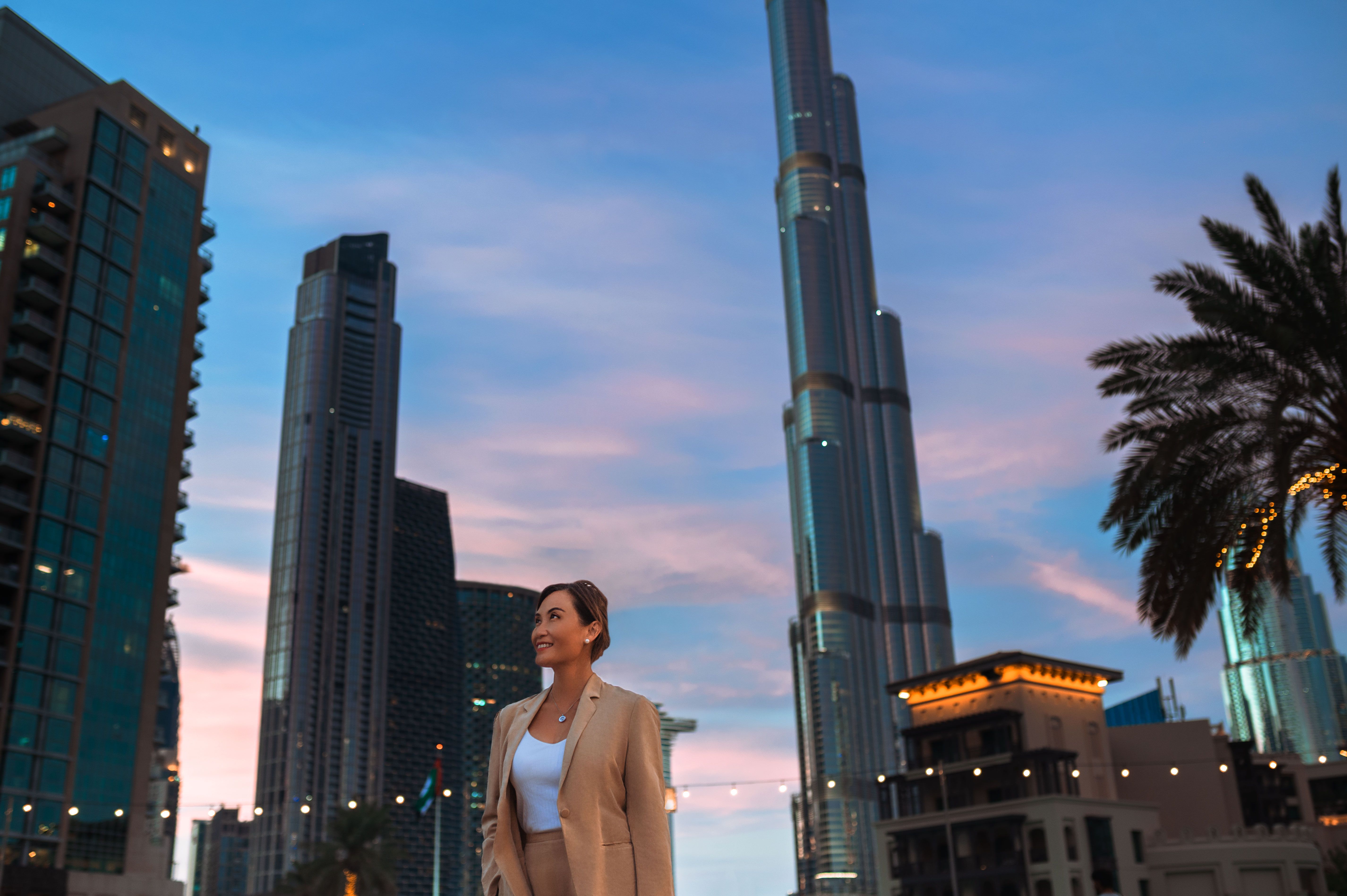 Cheerful asian businesswoman looking up, admiring ultramodern skyscrapers in city center at night