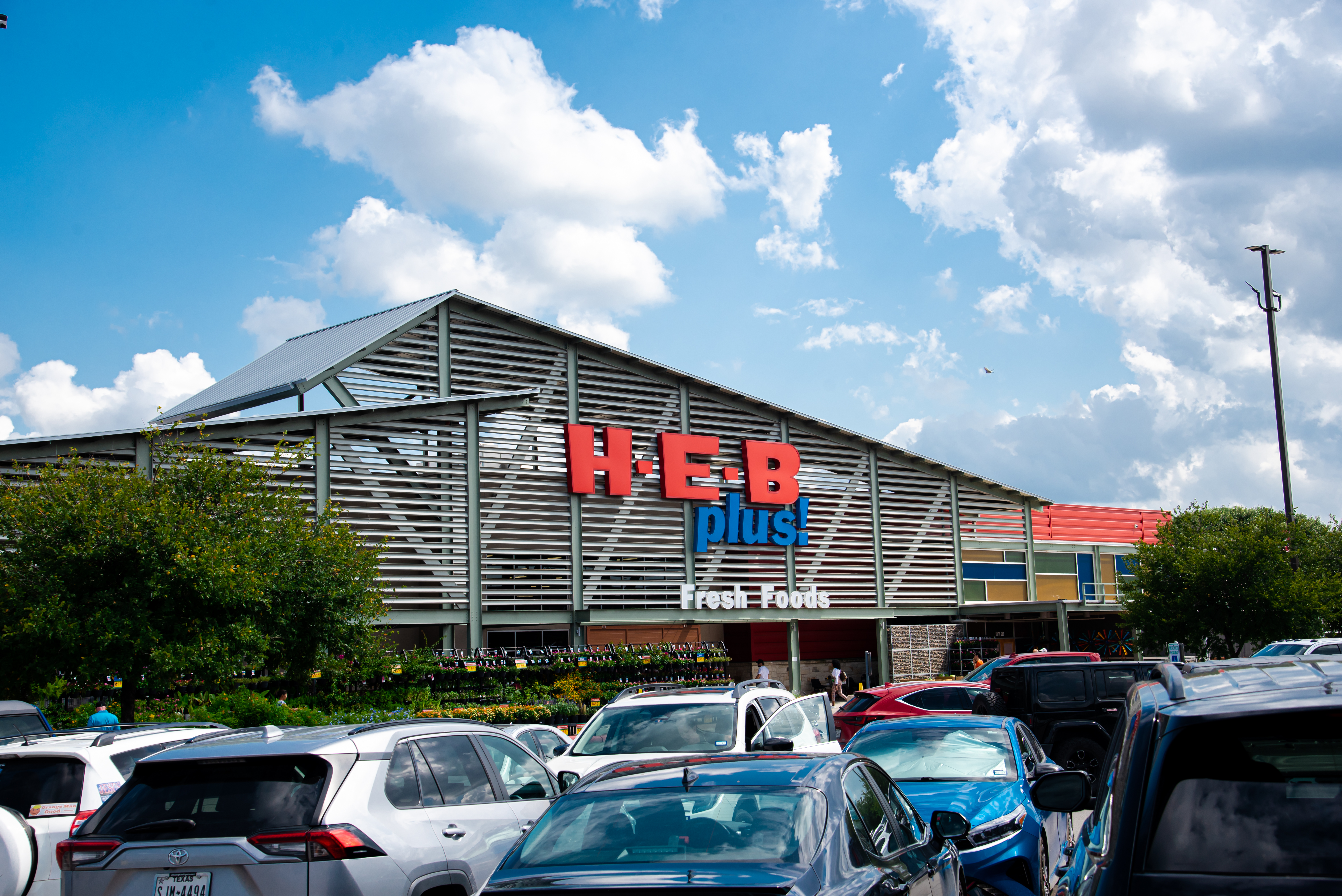 Entrada a la fachada de la tienda de comestibles H.E.B Plus desde los concurridos estacionamientos soleados cielo azul nube, cadena de supermercados privados con sede en San Antonio más de 380 tiendas en EE. UU. y México