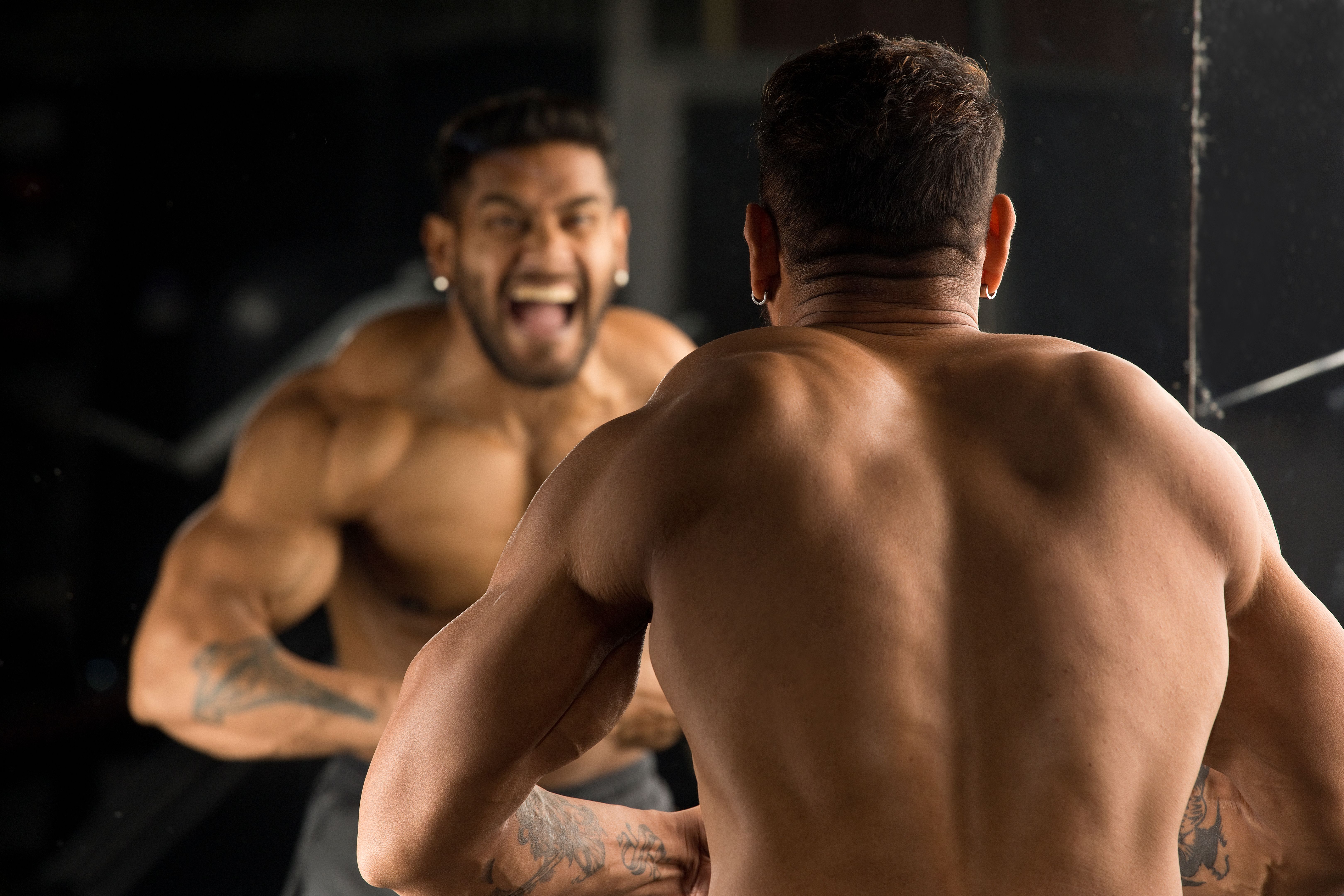 Muscular man flexing muscles in front of mirror