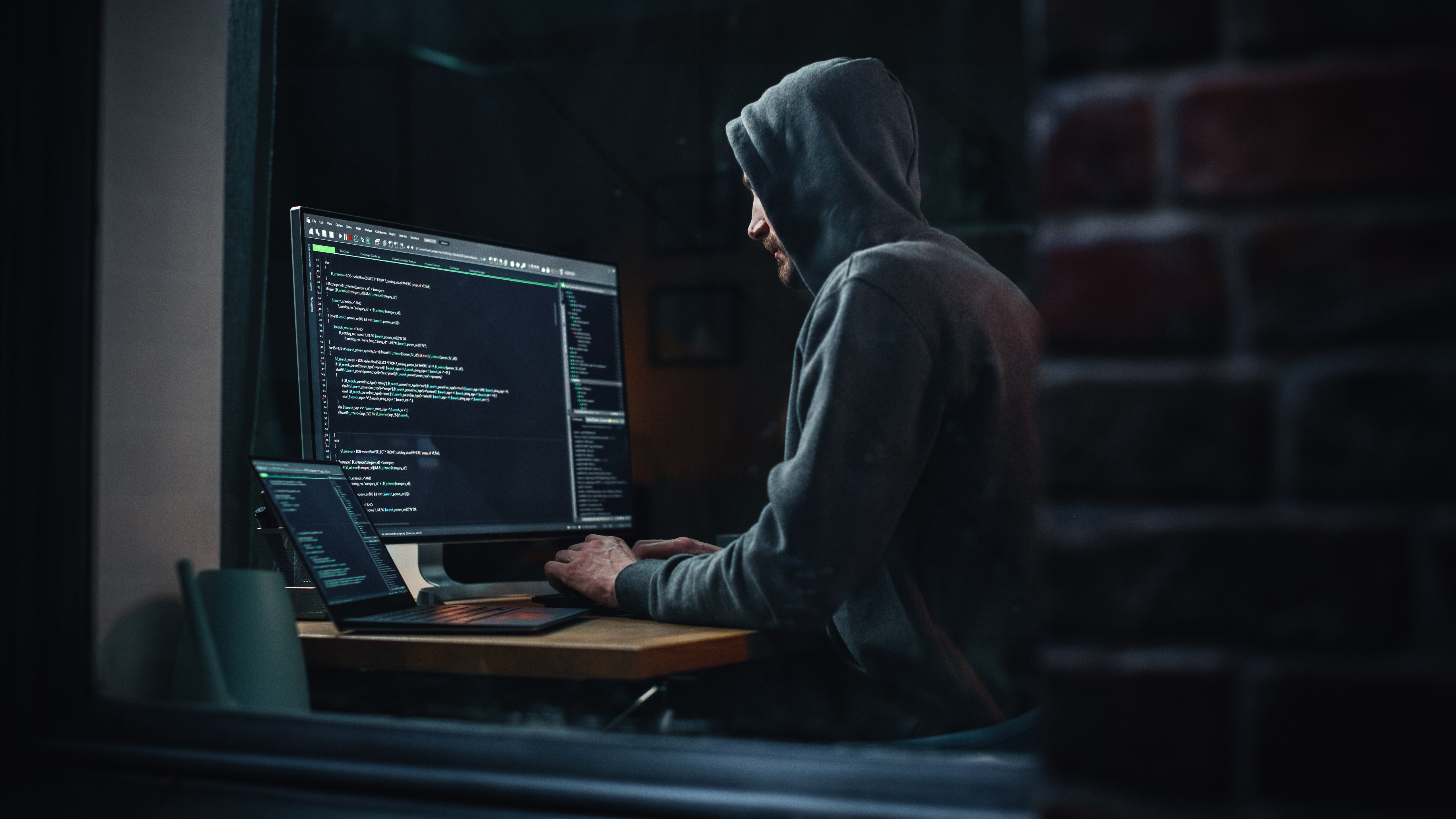 Night Apartment: Evil Greedy Hacker Wearing Hoodie, Breaks into Data Servers, Does DDOS Attack, Phishing Scheme, Malware, Sends Virus. Cyber Security and Crime Concept. View From Outdoors into Window. Night Apartment: Evil Greedy Hacker Wearing Hoodie, Breaks into Data Servers, Does DDOS Attack, Phishing Scheme, Malware, Sends Virus. Cyber Security and Crime Concept. View From Outdoors into Window.