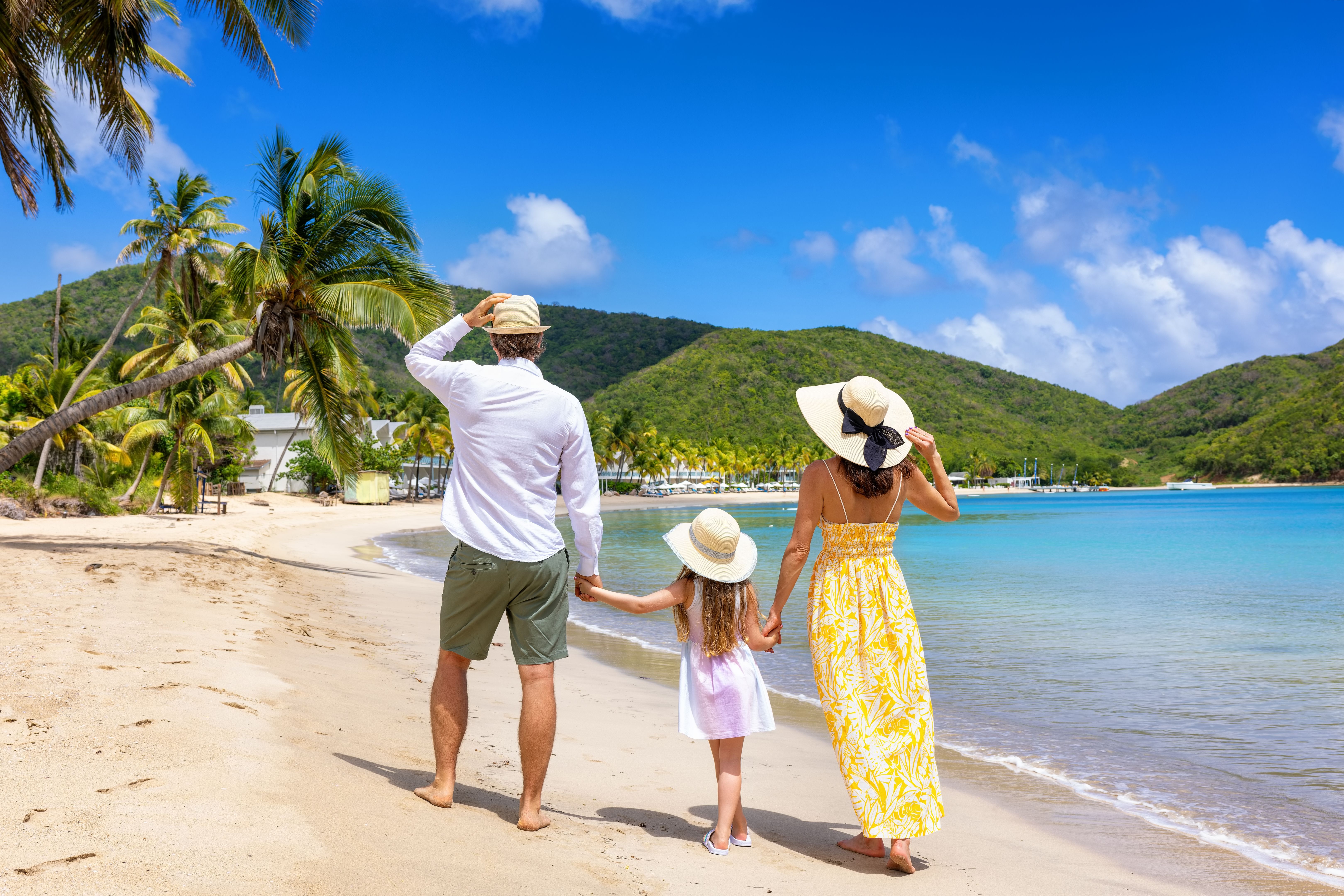 A holiday family walks at a tropical beach with coconut palm trees