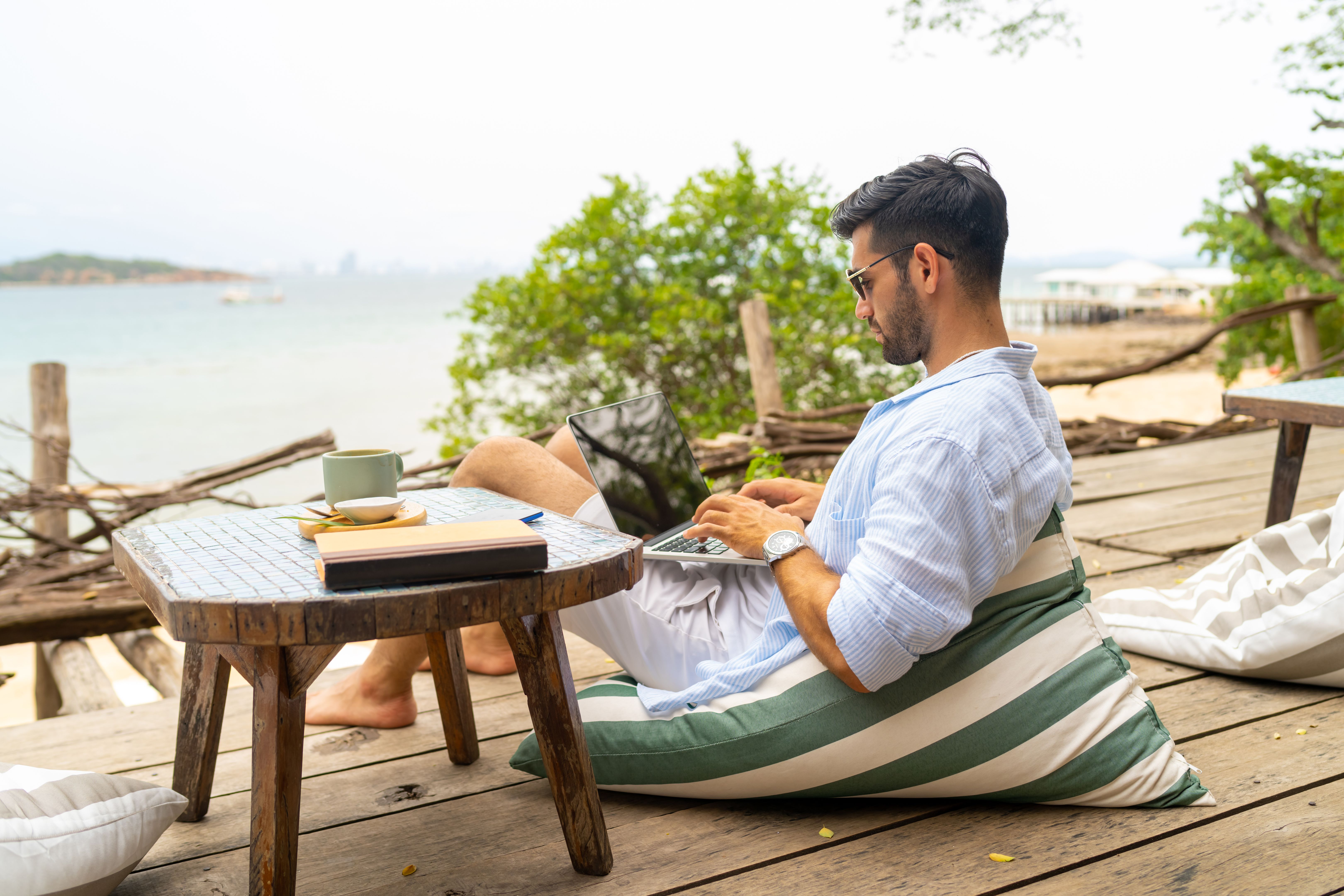 Businessman working on laptop at tropical island on summer holiday vacation.