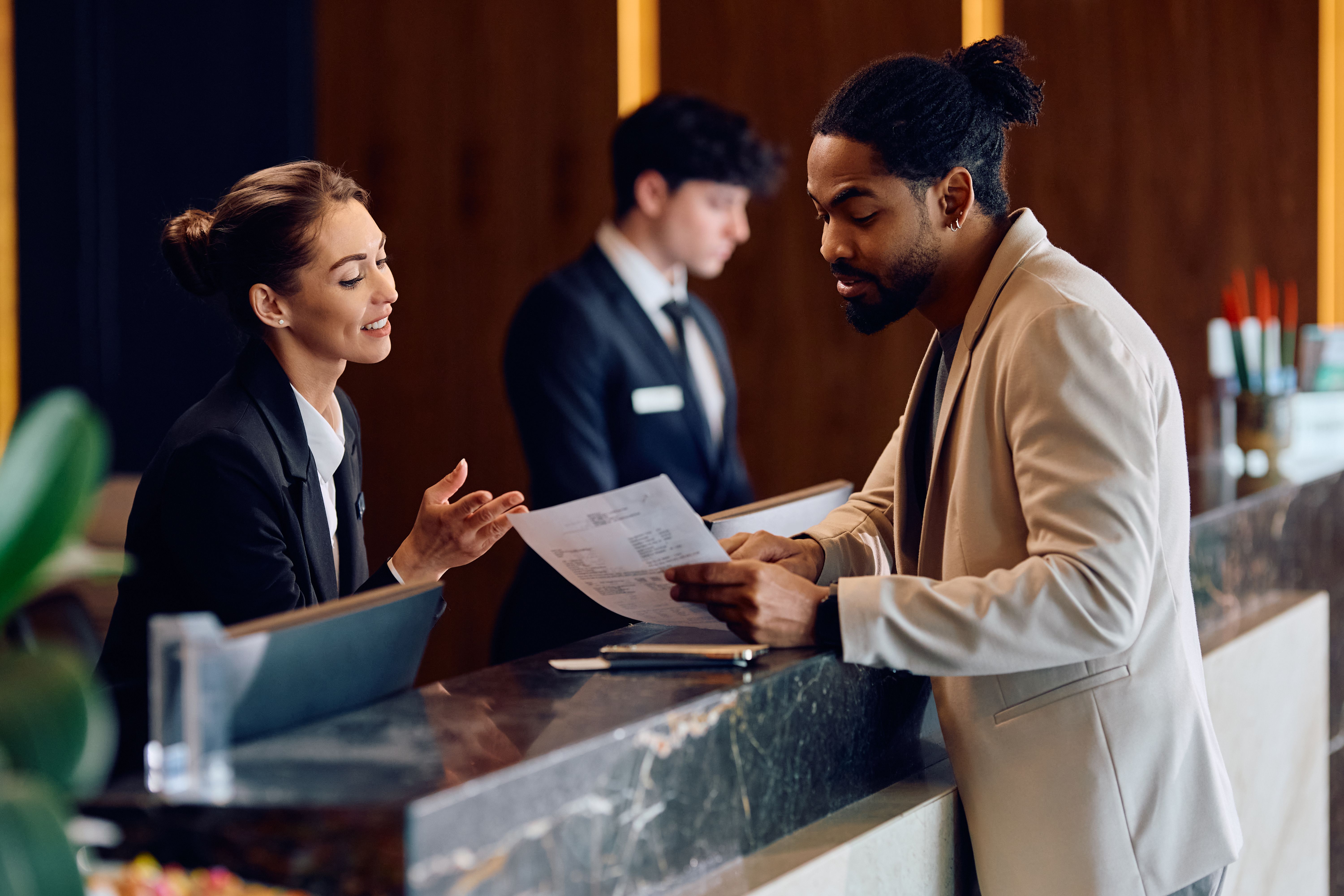 African American man checking in at reception desk in a hotel. African American man checking in at reception desk in a hotel.
