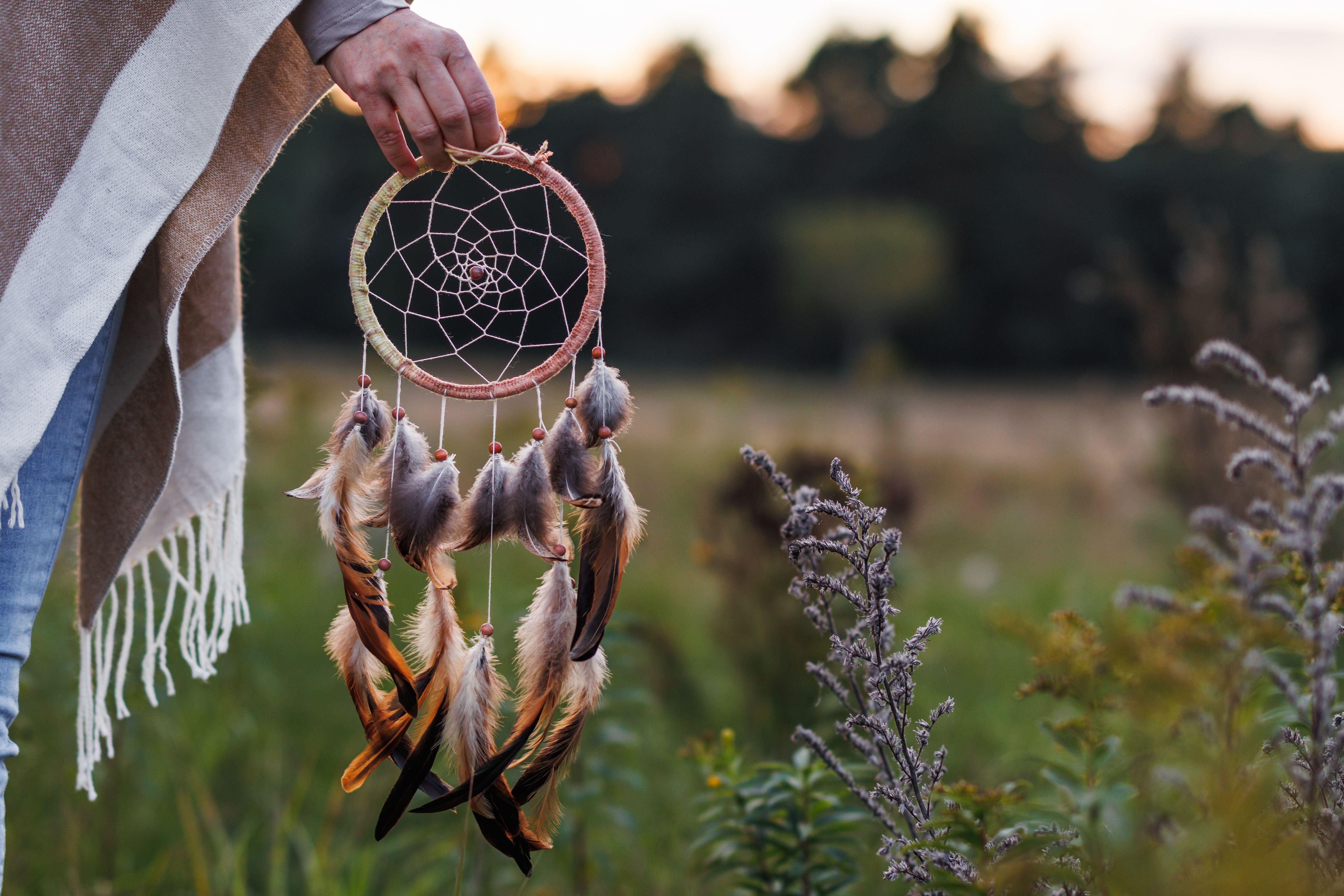 Woman with poncho holding dreamcatcher outdoors
