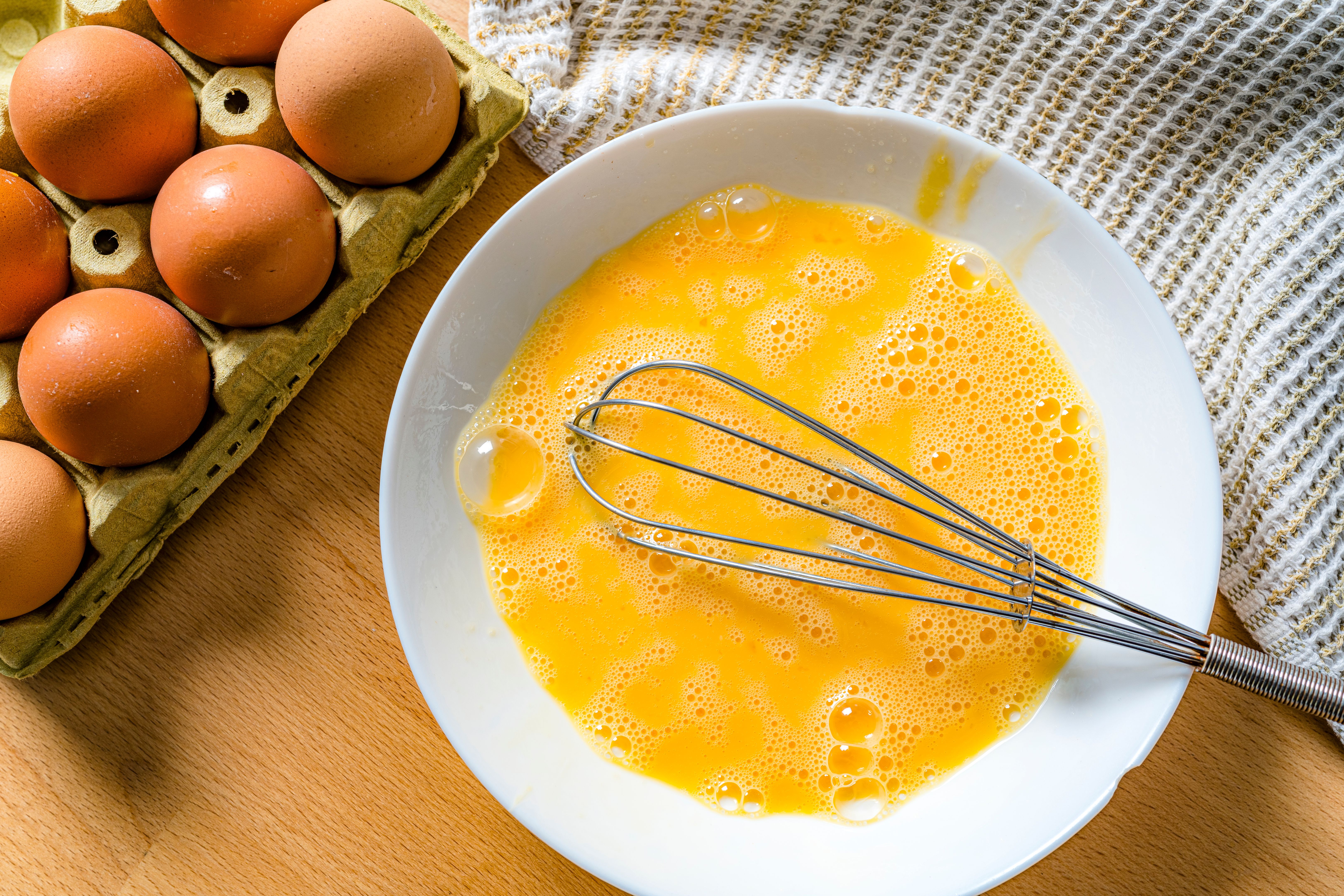 Overhead shot of scrambled raw eggs in a white bowl