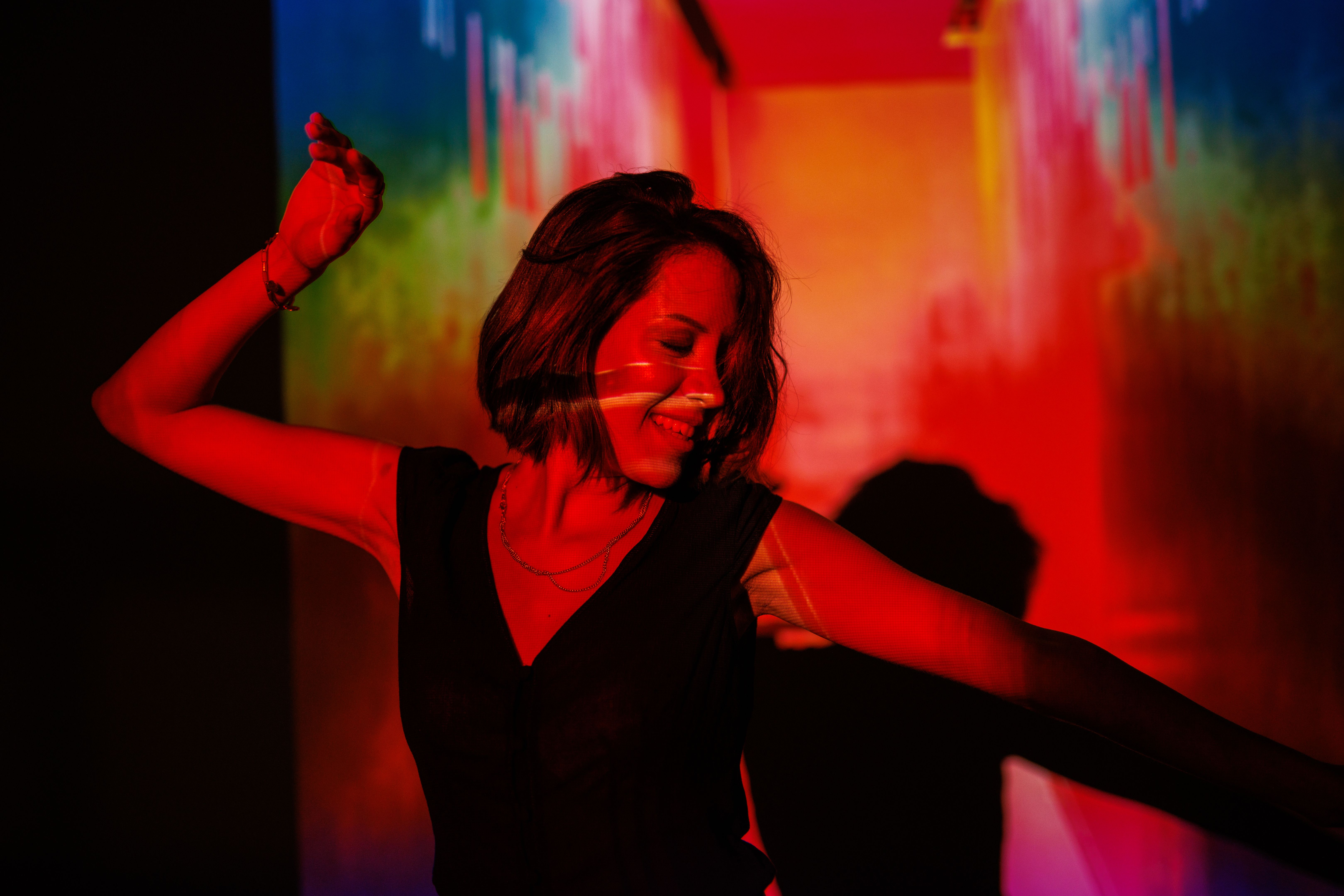 Woman dancing under vibrant red and multicolored lighting in a lively setting