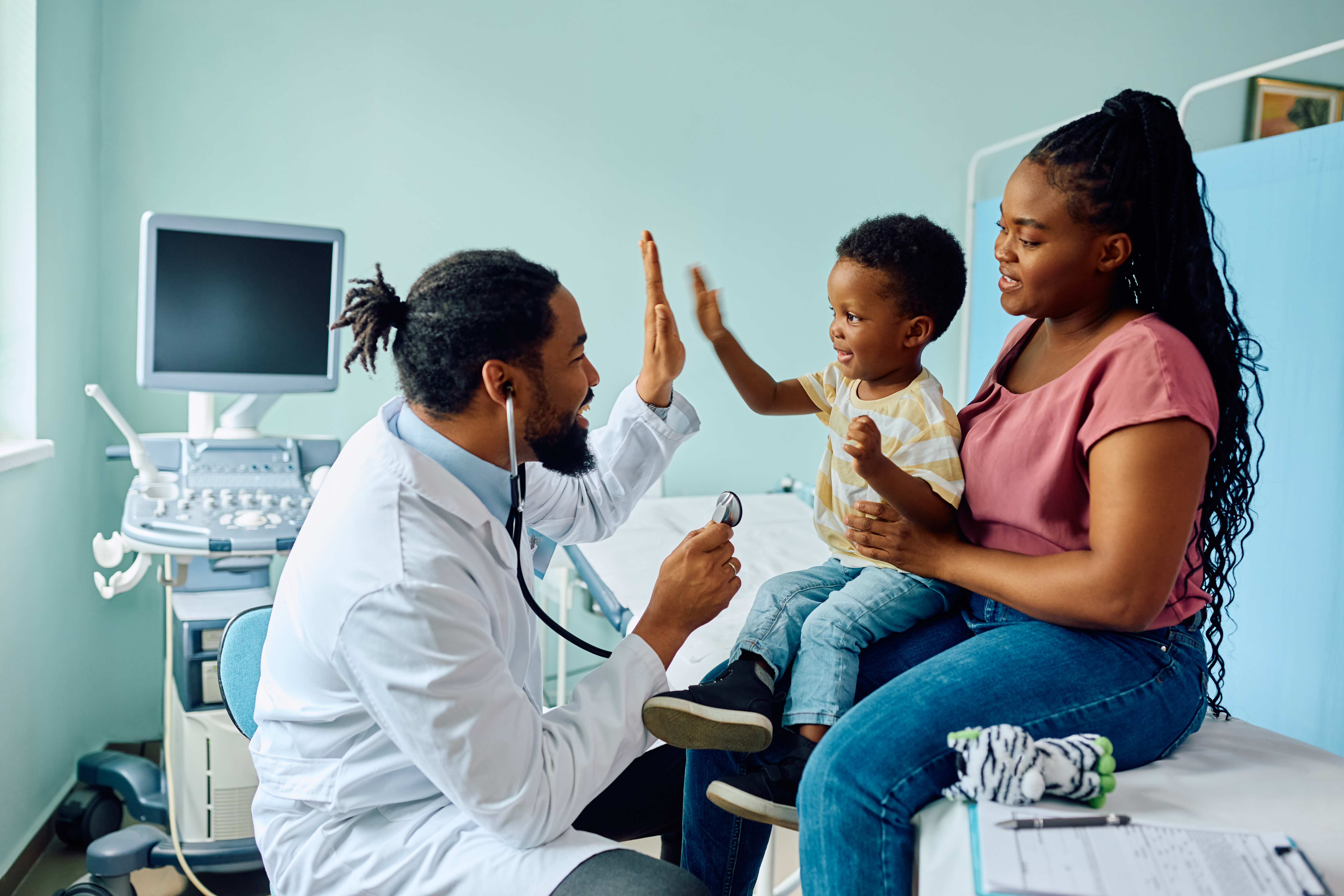 Happy black boy giving high five to his pediatrician after medical examination at doctor's office. Happy black boy giving high five to his pediatrician after medical examination at doctor's office.