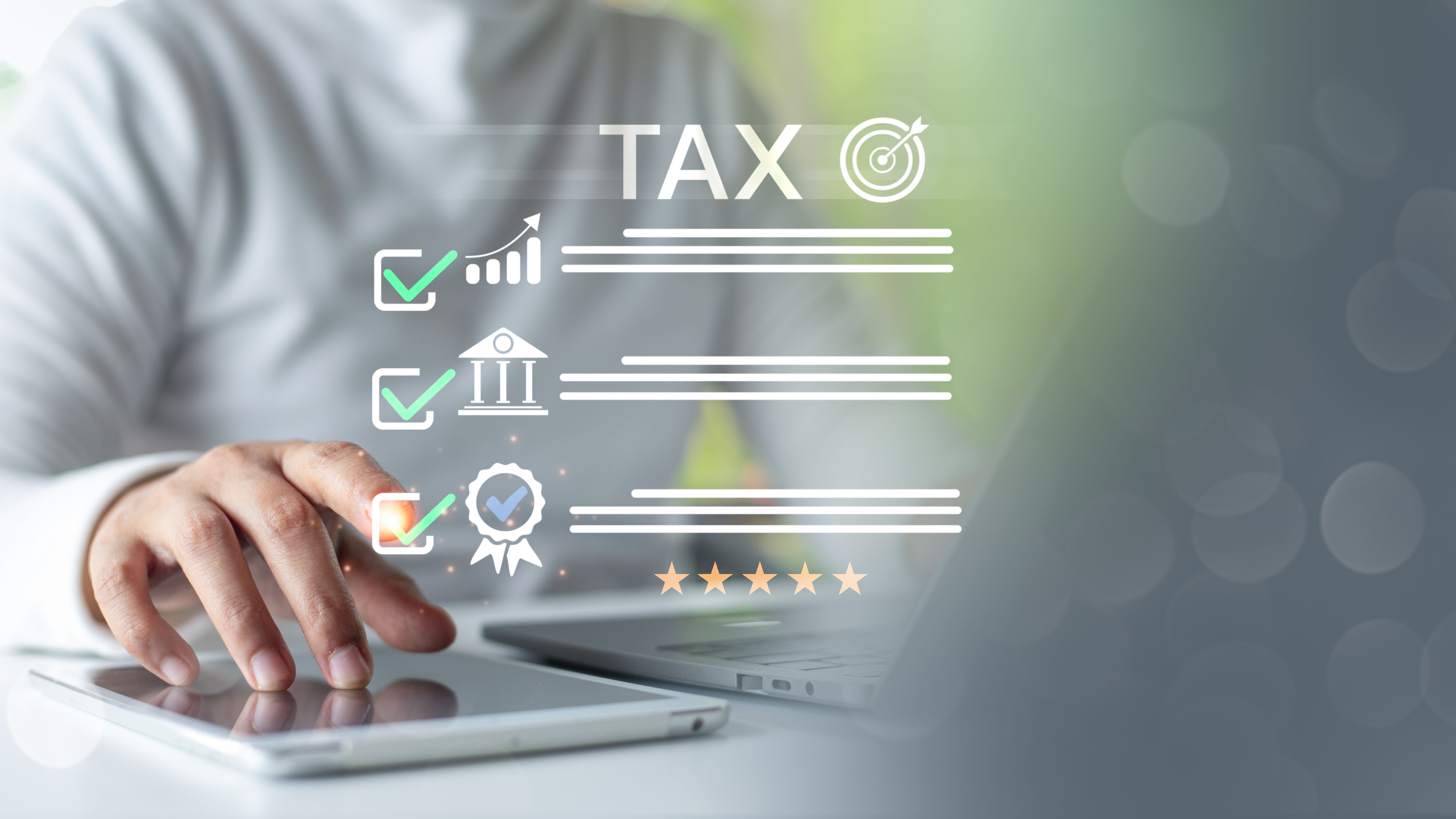 Hand using tablet and laptop with tax checklist and quality icons, representing digital tax planning, e-filing, and financial goal achievement.