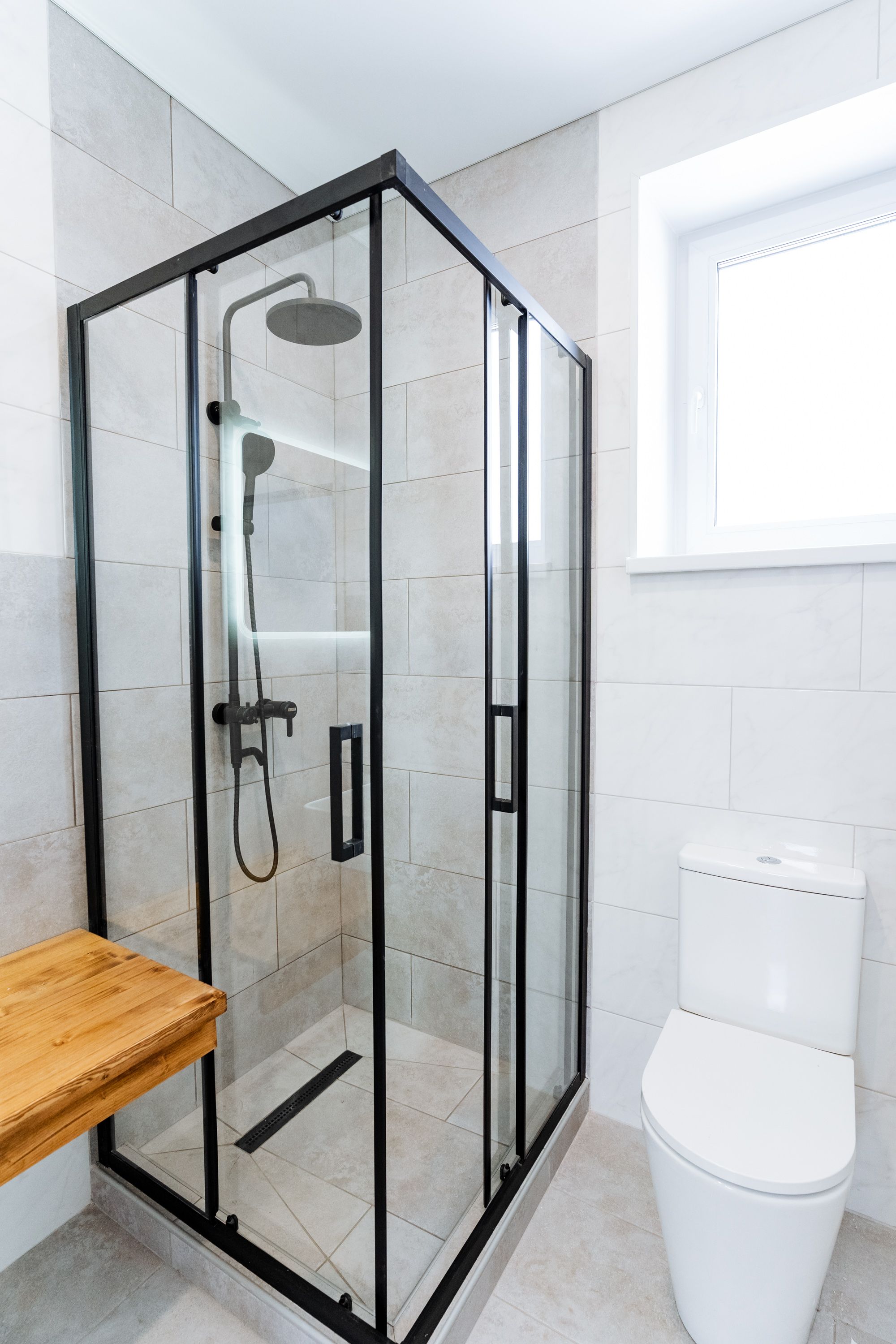 Bathroom with shower stall, toilet, shower door, and plumbing fixtures