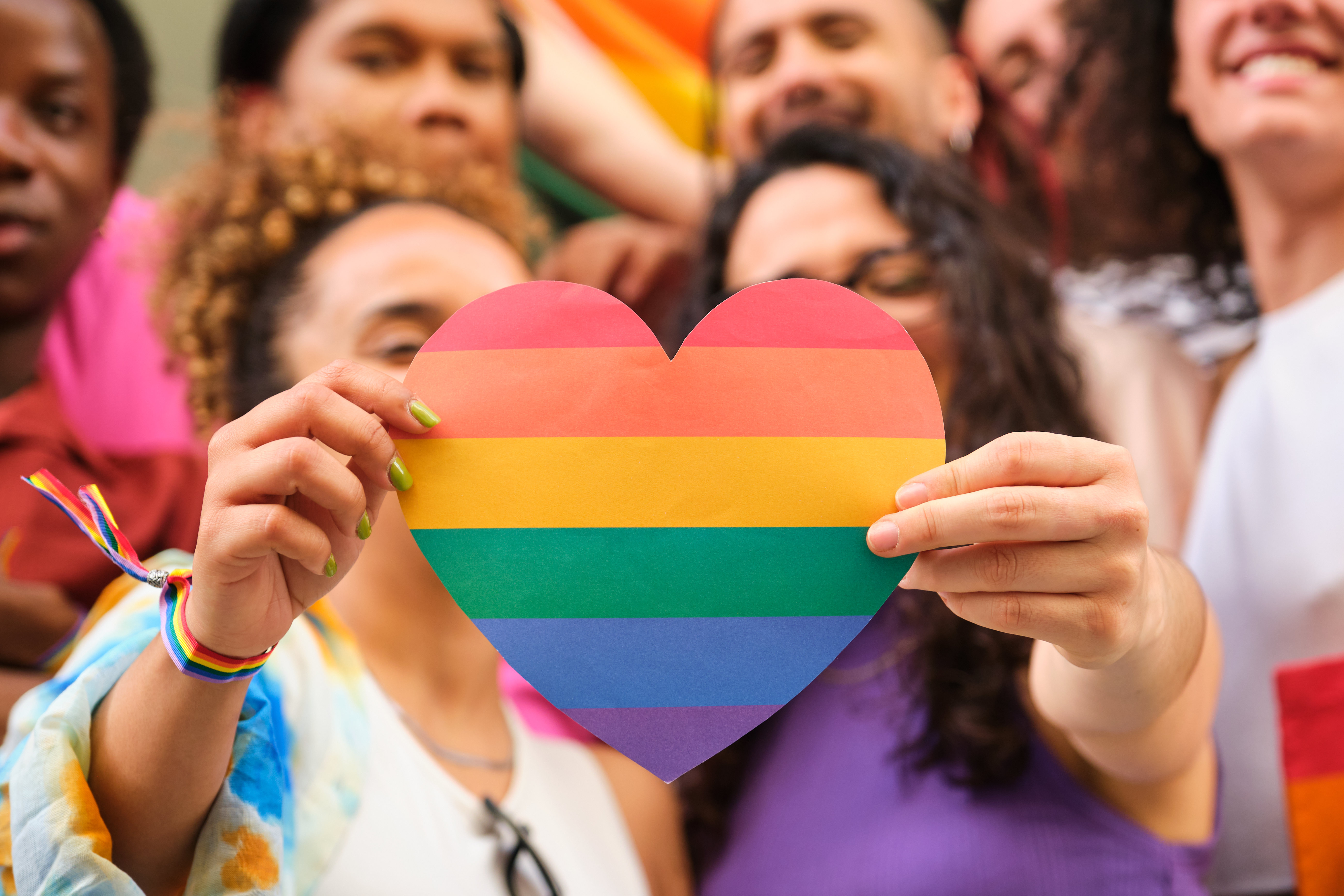 A group of LGBTQ people holding a rainbow heart celebrating Pride Month. A group of LGBTQ people holding a rainbow heart celebrating Pride Month.