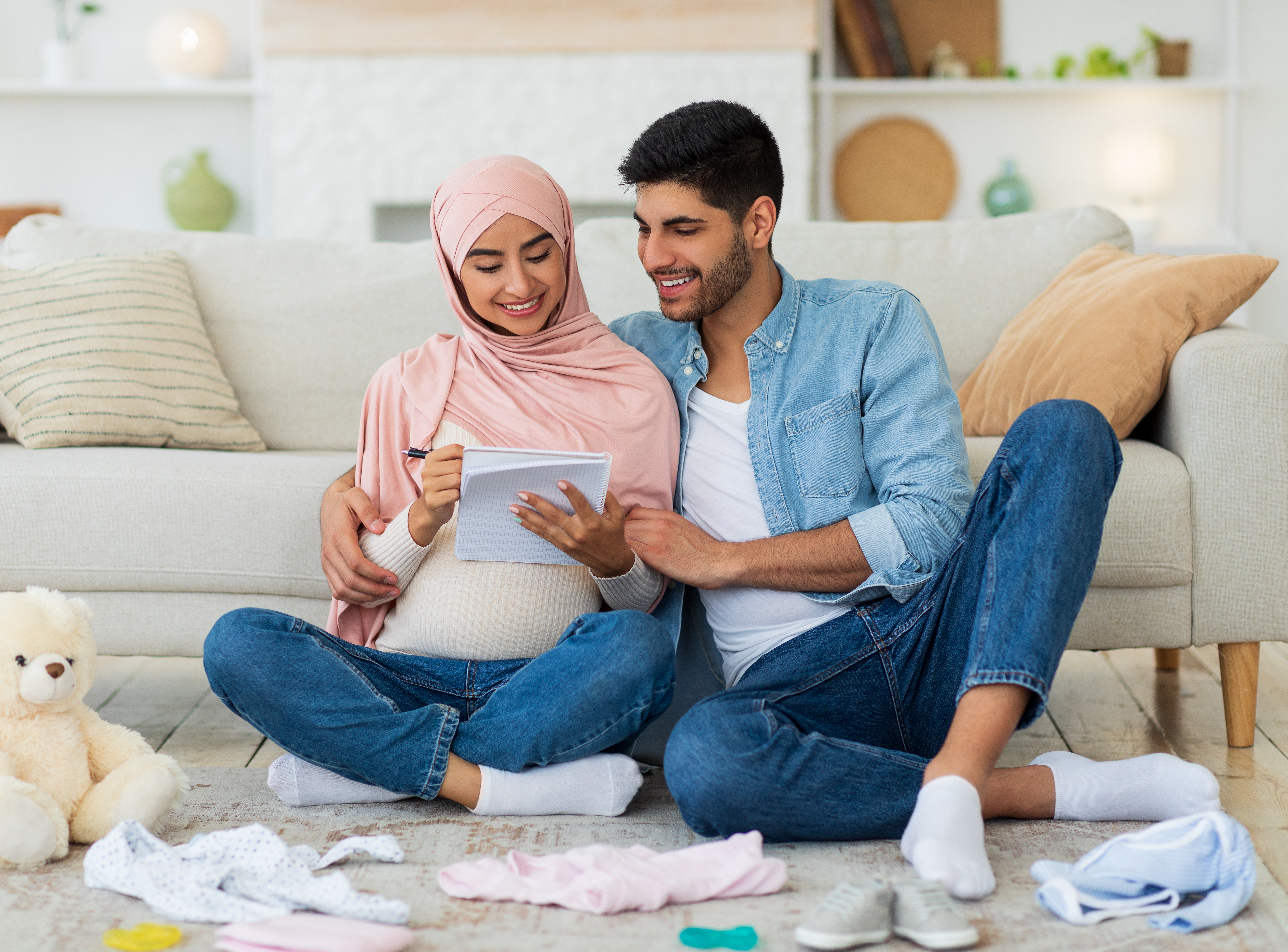Preparing for childbirth. Pregnant muslim couple making checklist of baby things before going to maternity hospital Preparing for childbirth. Pregnant muslim couple making checklist of baby things before going to maternity hospital