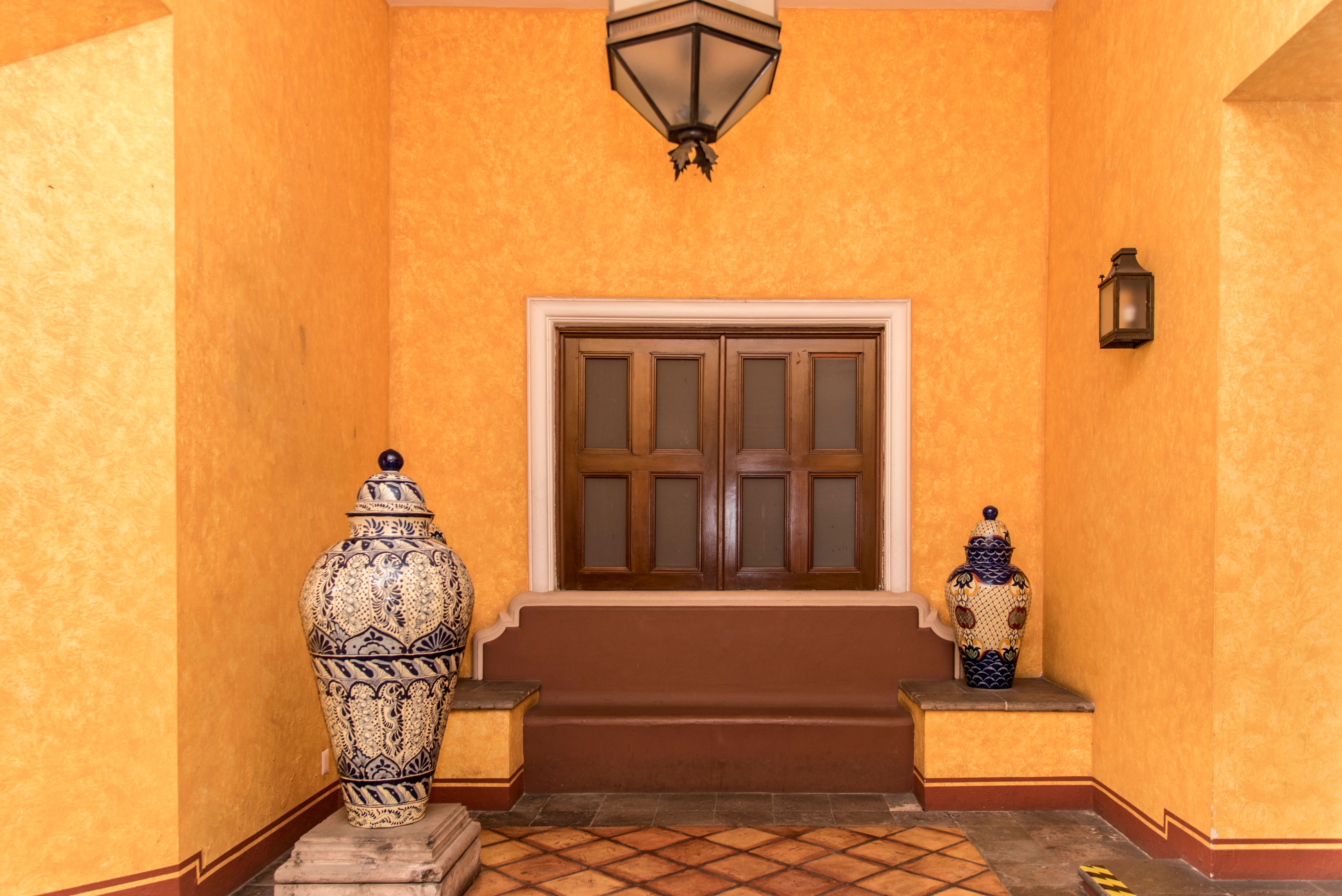 A yellow room with a blue and white vase on a table