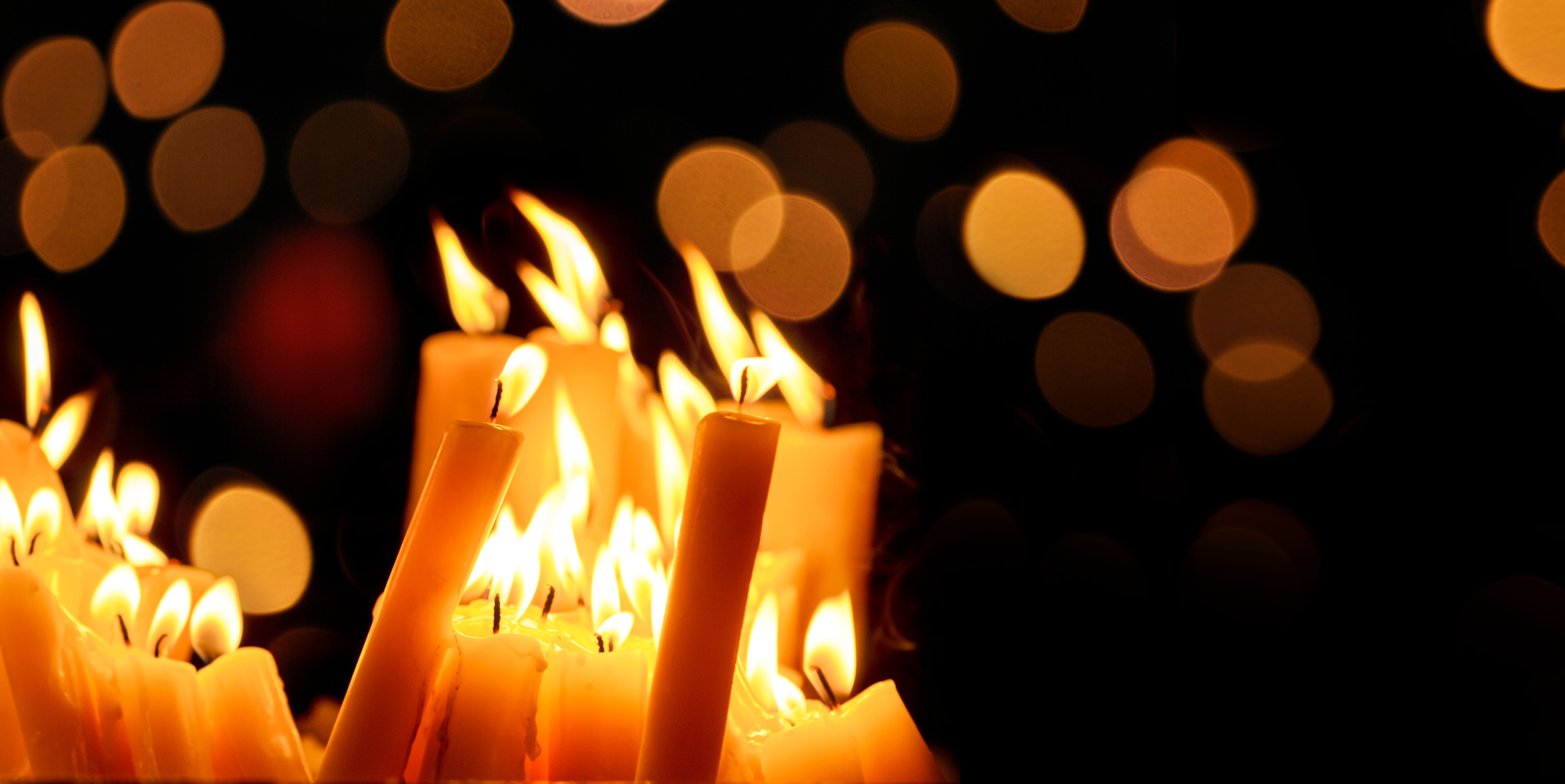 Religious candle light on black background. Yellow candlelight flame in dark christian church at night. Religious candle light on black background. Yellow candlelight flame in dark christian church at night.