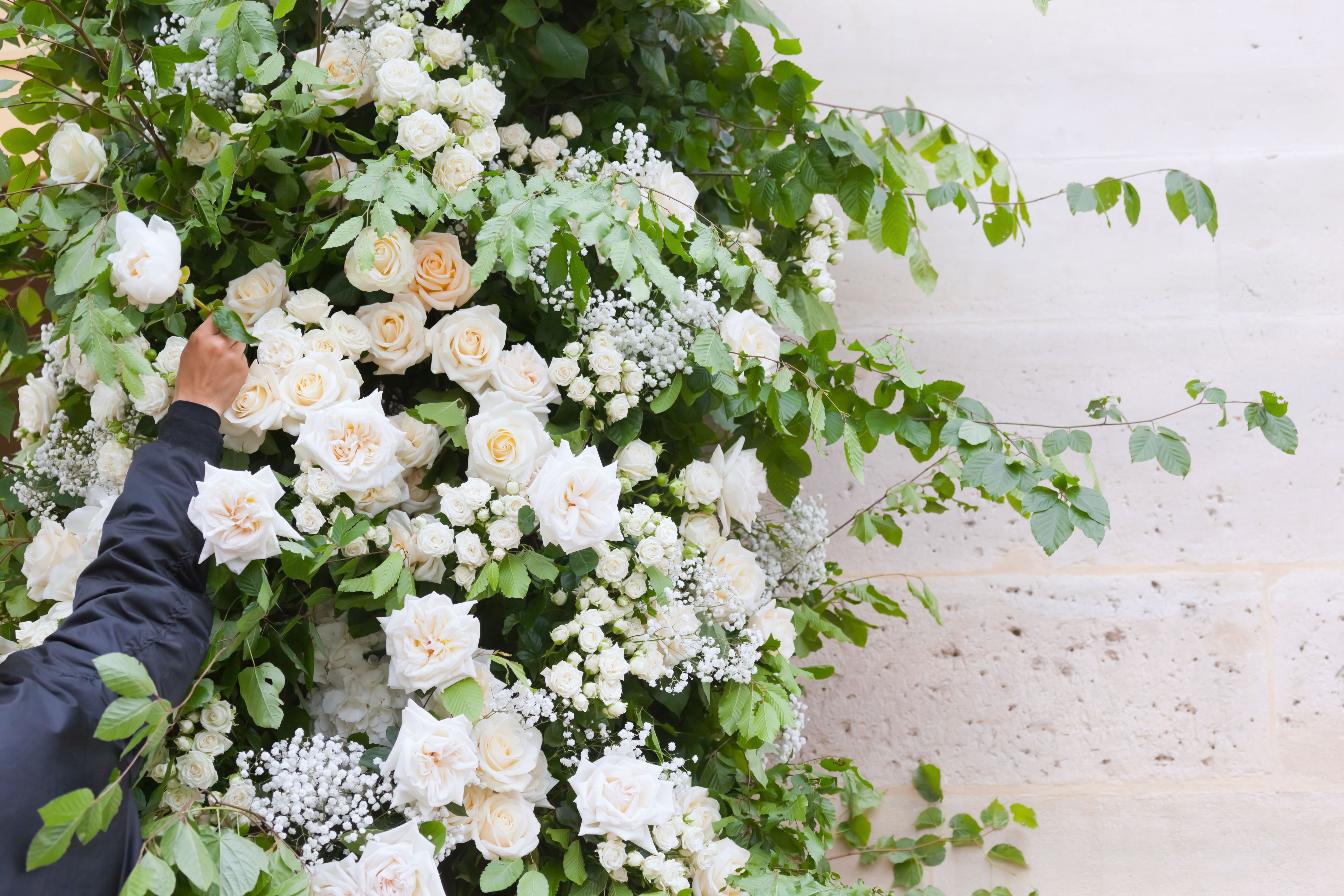 Wedding Florist Decorates the Church Entrance Inserting White Flowers into the Greenery