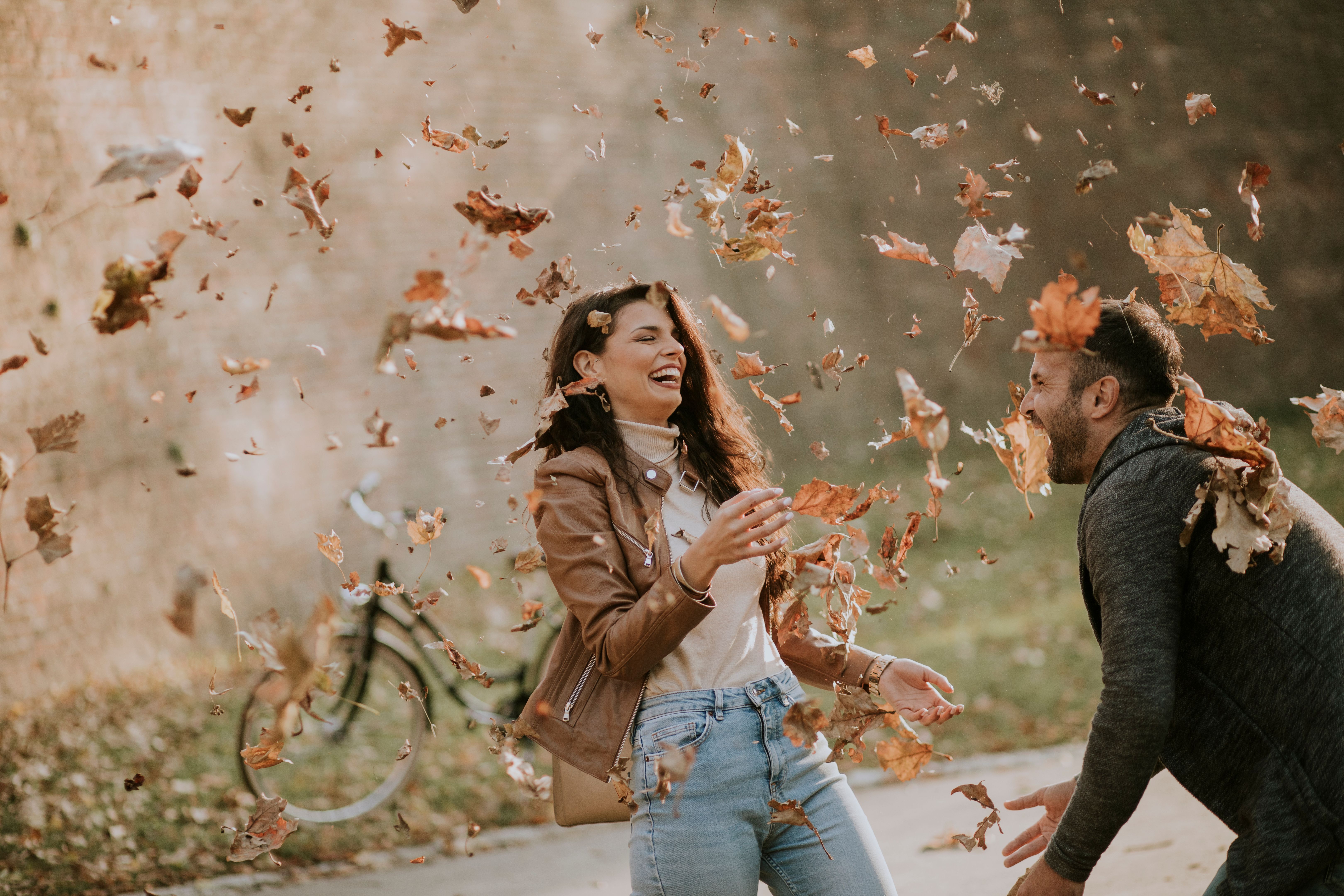 Young couple having fun with autumn leaves in the park