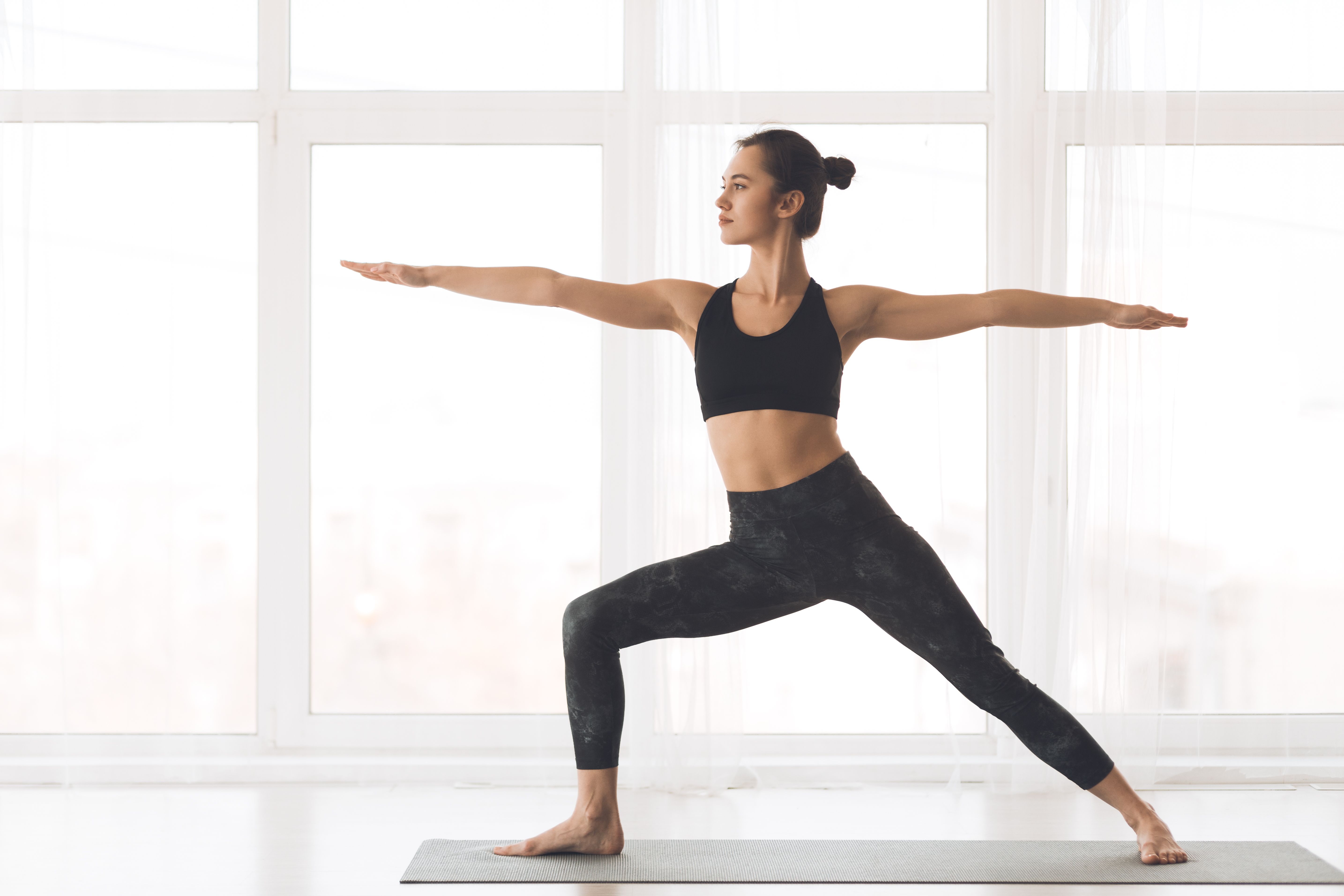 Young Woman Practicing Warrior Pose in Bright Indoor Studio During Yoga Session
