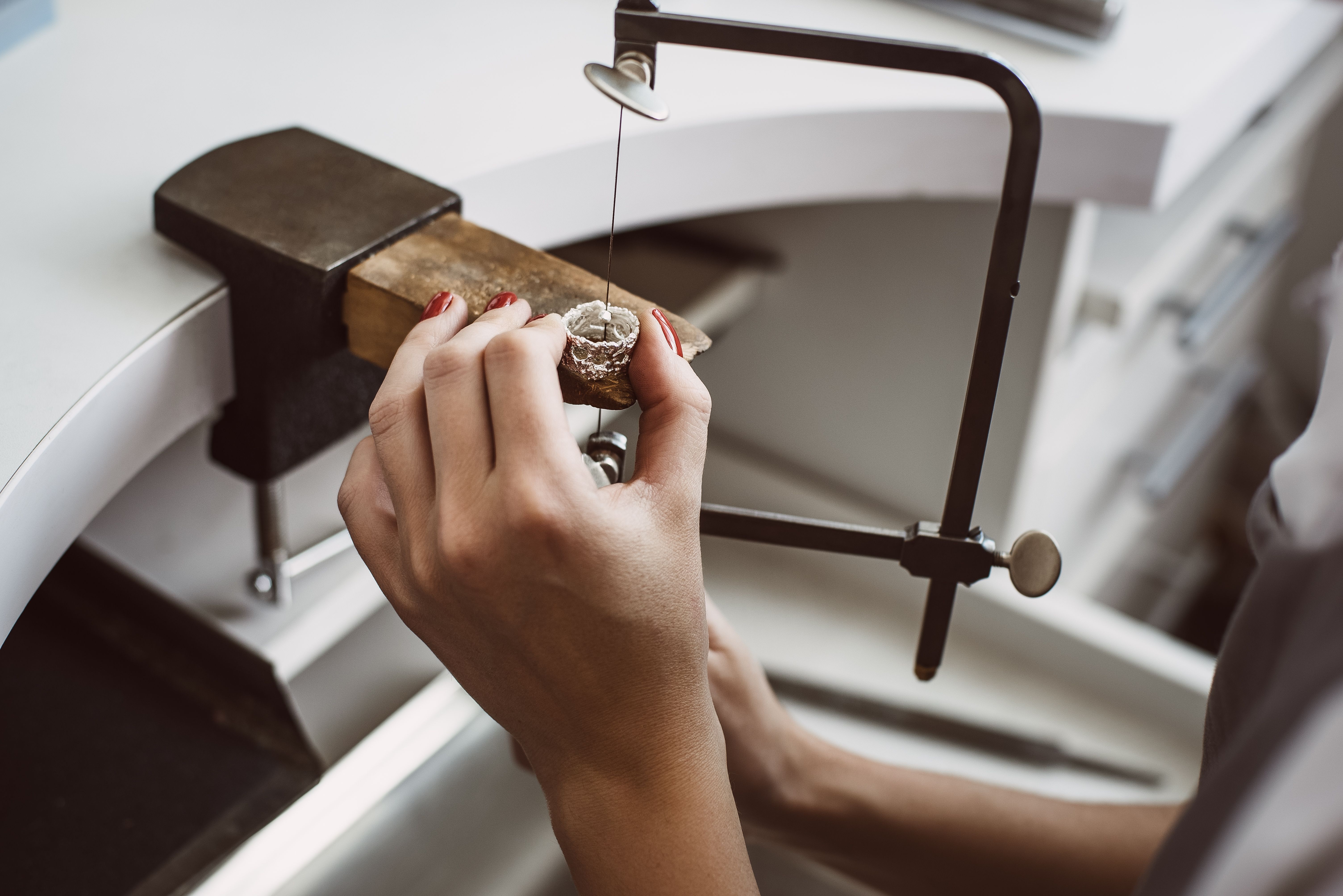 Master's hand. Close up of a female jeweler's hands working on a ring at her workbench.