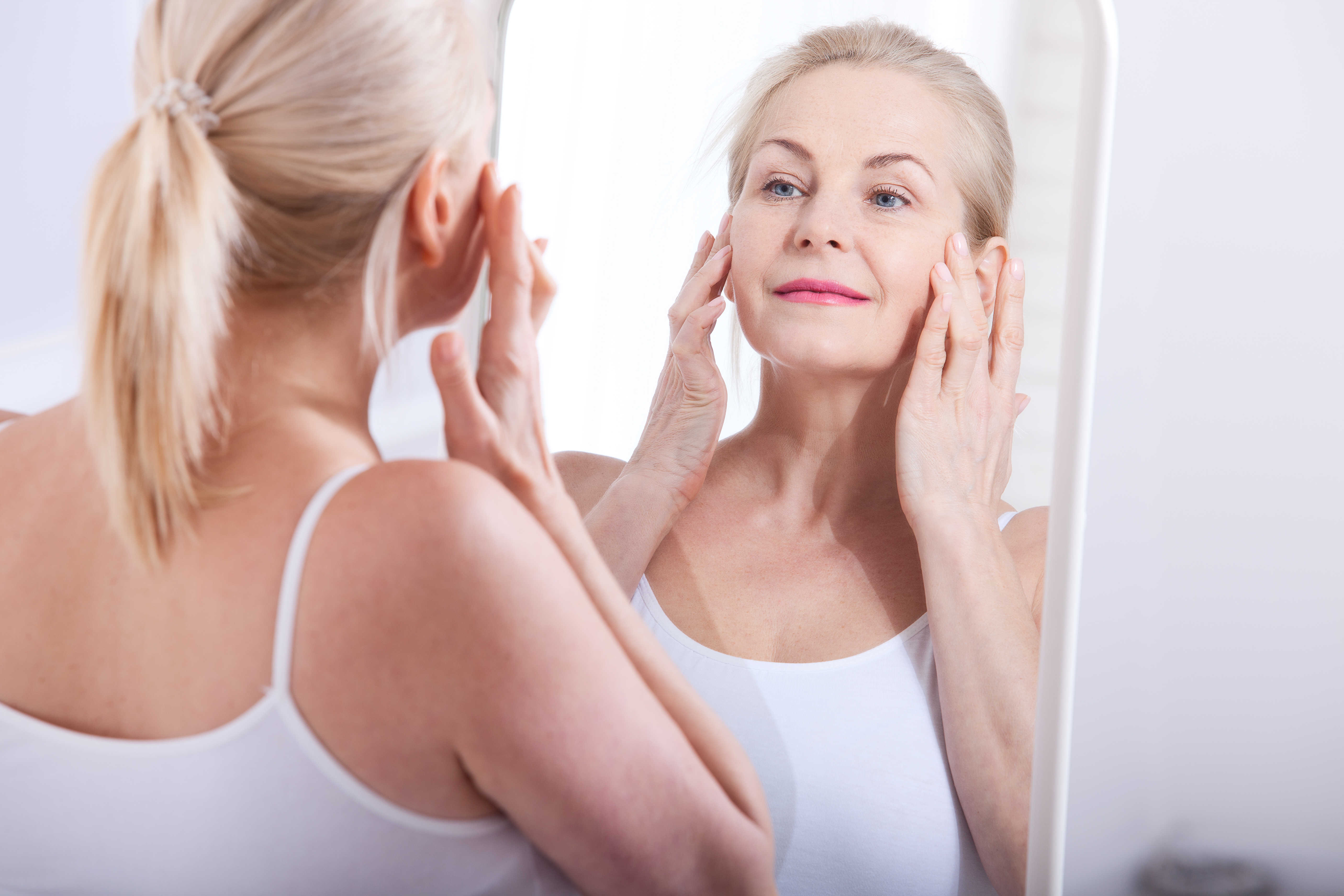 Middle aged woman looking at wrinkles in mirror. Plastic surgery and collagen injections. Makeup. Macro face. Selective focus Middle aged woman looking at wrinkles in mirror. Plastic surgery and collagen injections. Makeup. Macro face. Selective focus