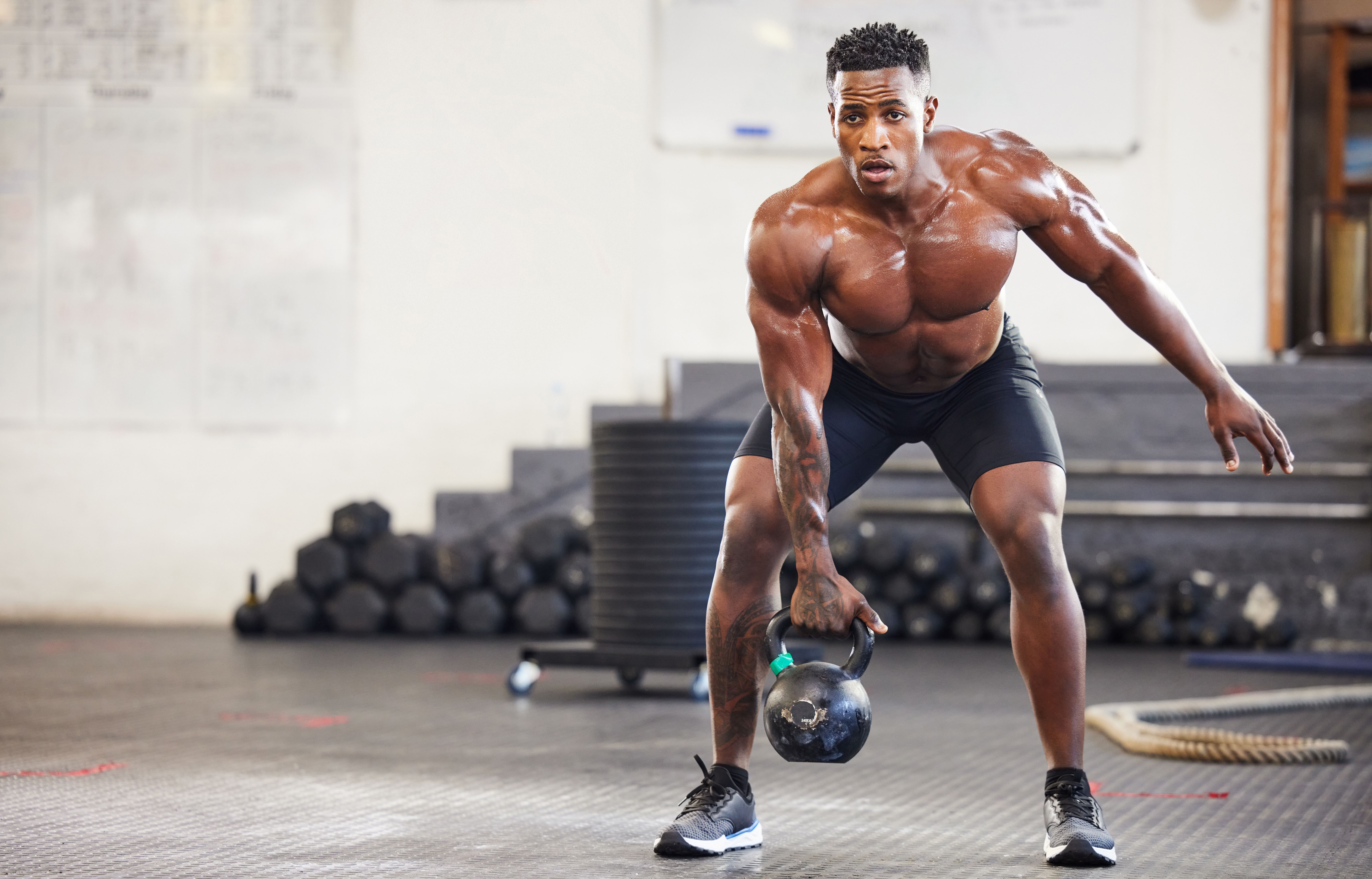Shot of a muscular young man exercising with a kettlebell in a gym