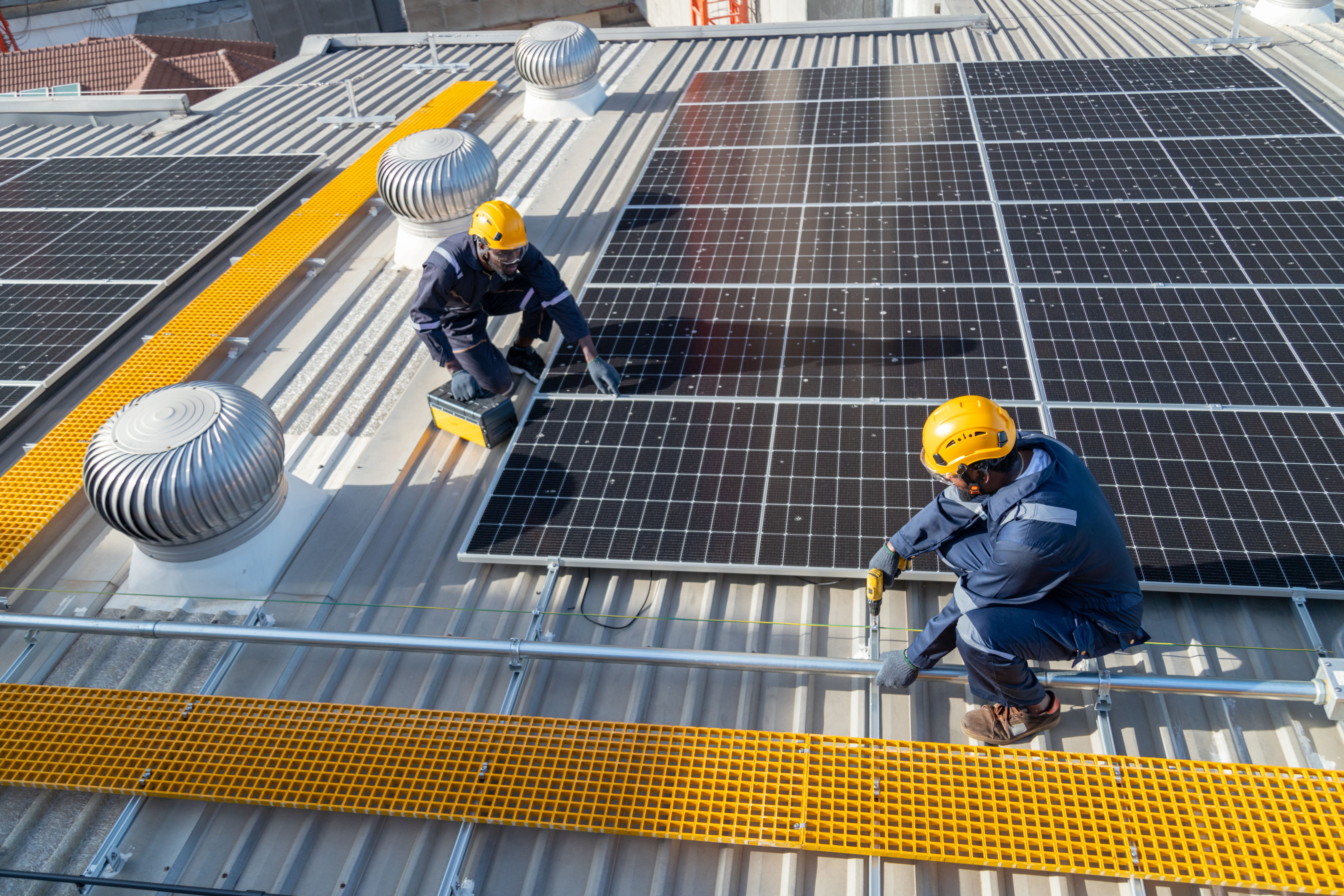Engineers and technicians check drawings for installing solar cell panels on the roof.
