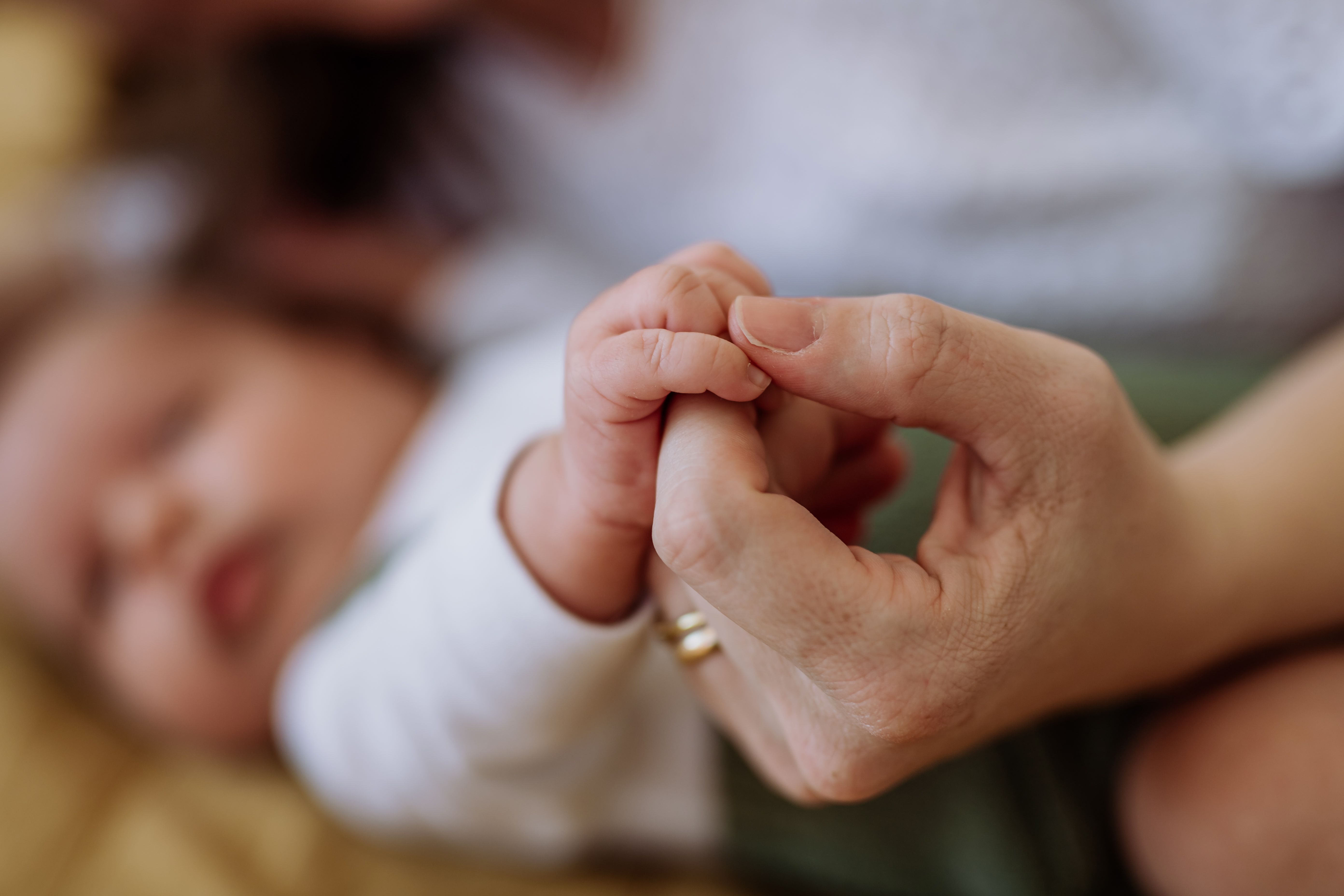 Close up of mother holding hand of her newborn baby.
