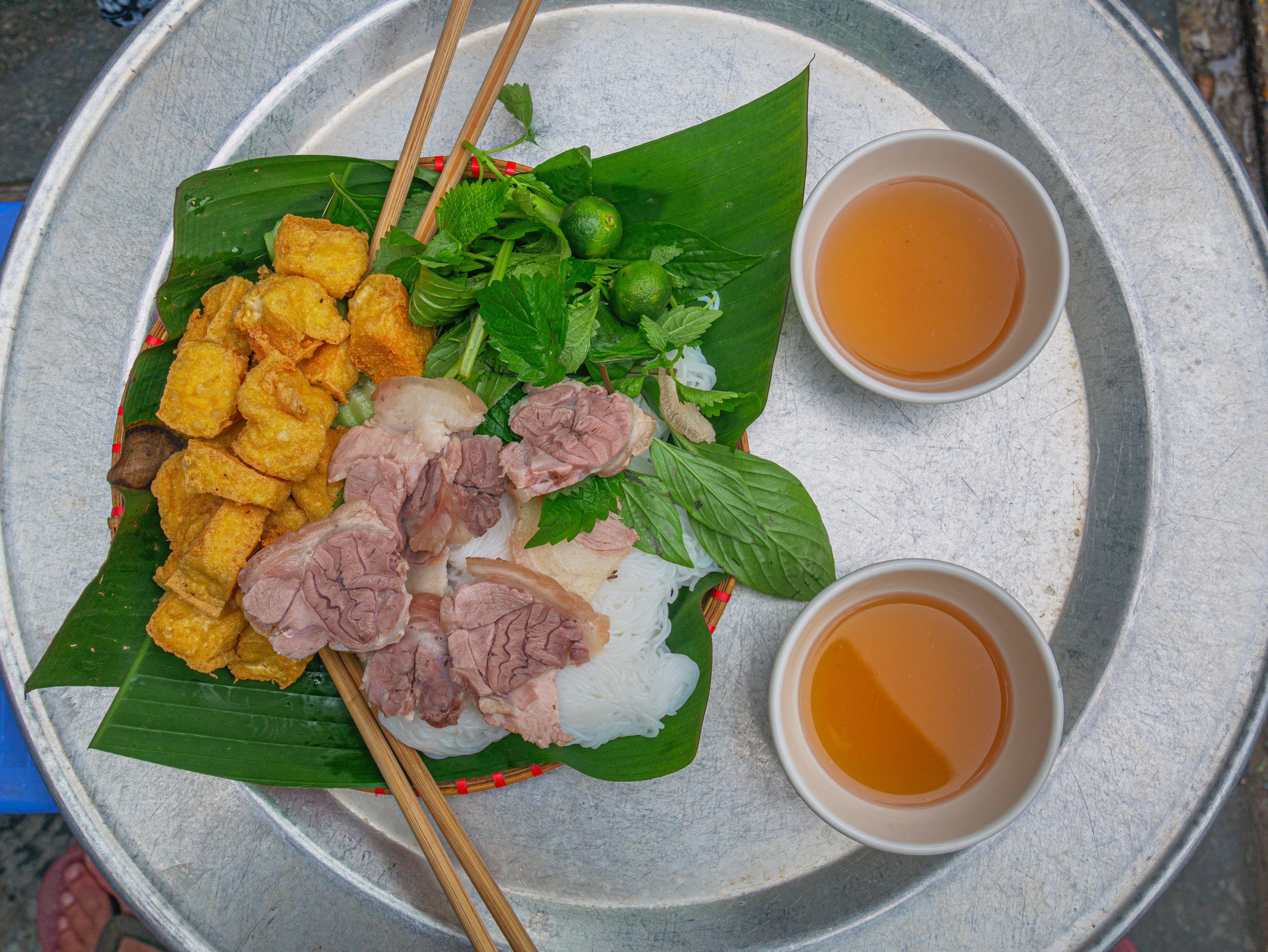 Bun Cha, traditional vietnamese dish served for lunch as street food in Hanoi. Minced pork fried tofu rice noodles herbs on banana leaf and soup.