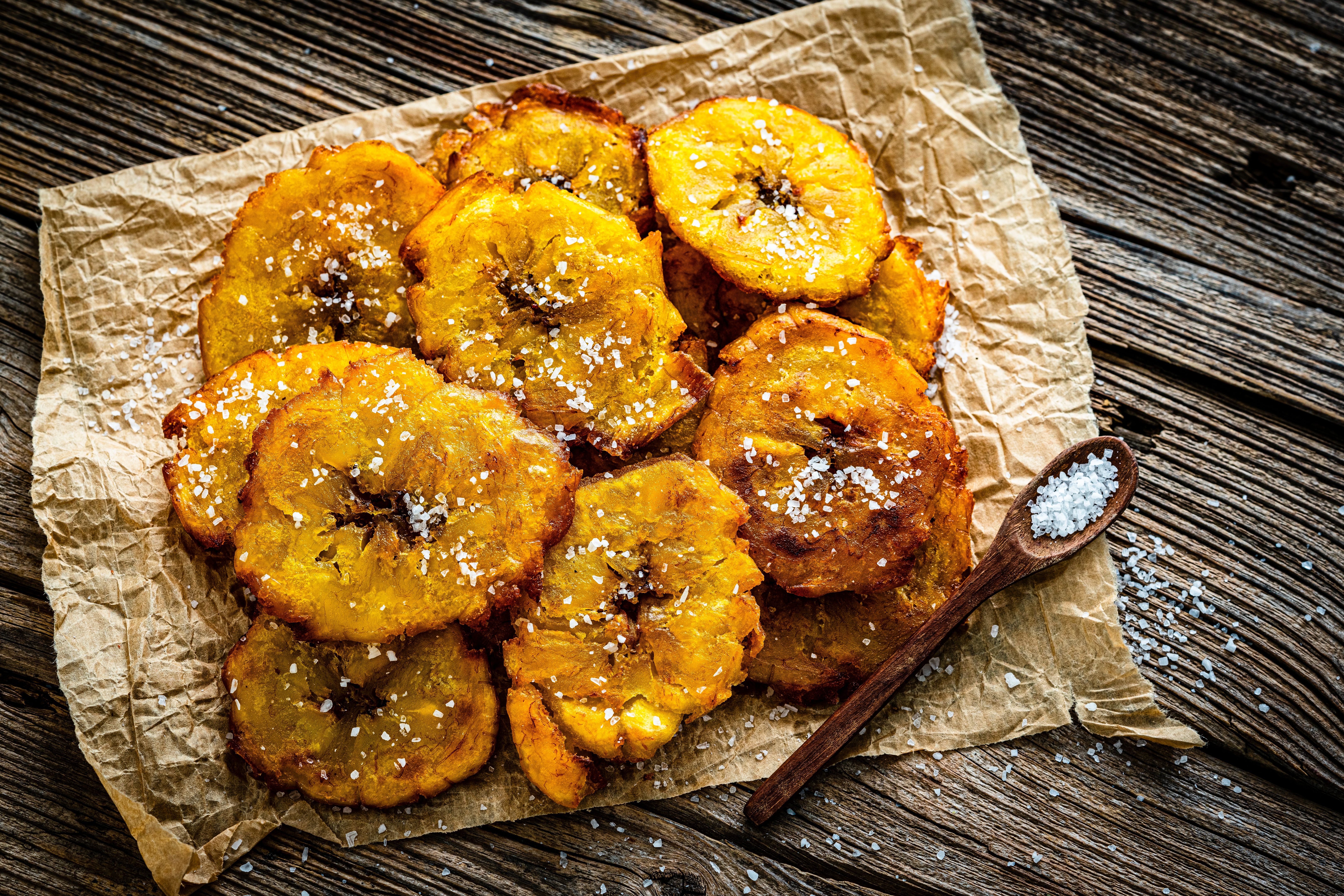 Fried tostones heap on rustic wooden table. Typical Latin American meal made from green plantains Fried tostones heap on rustic wooden table. Typical Latin American meal made from green plantains