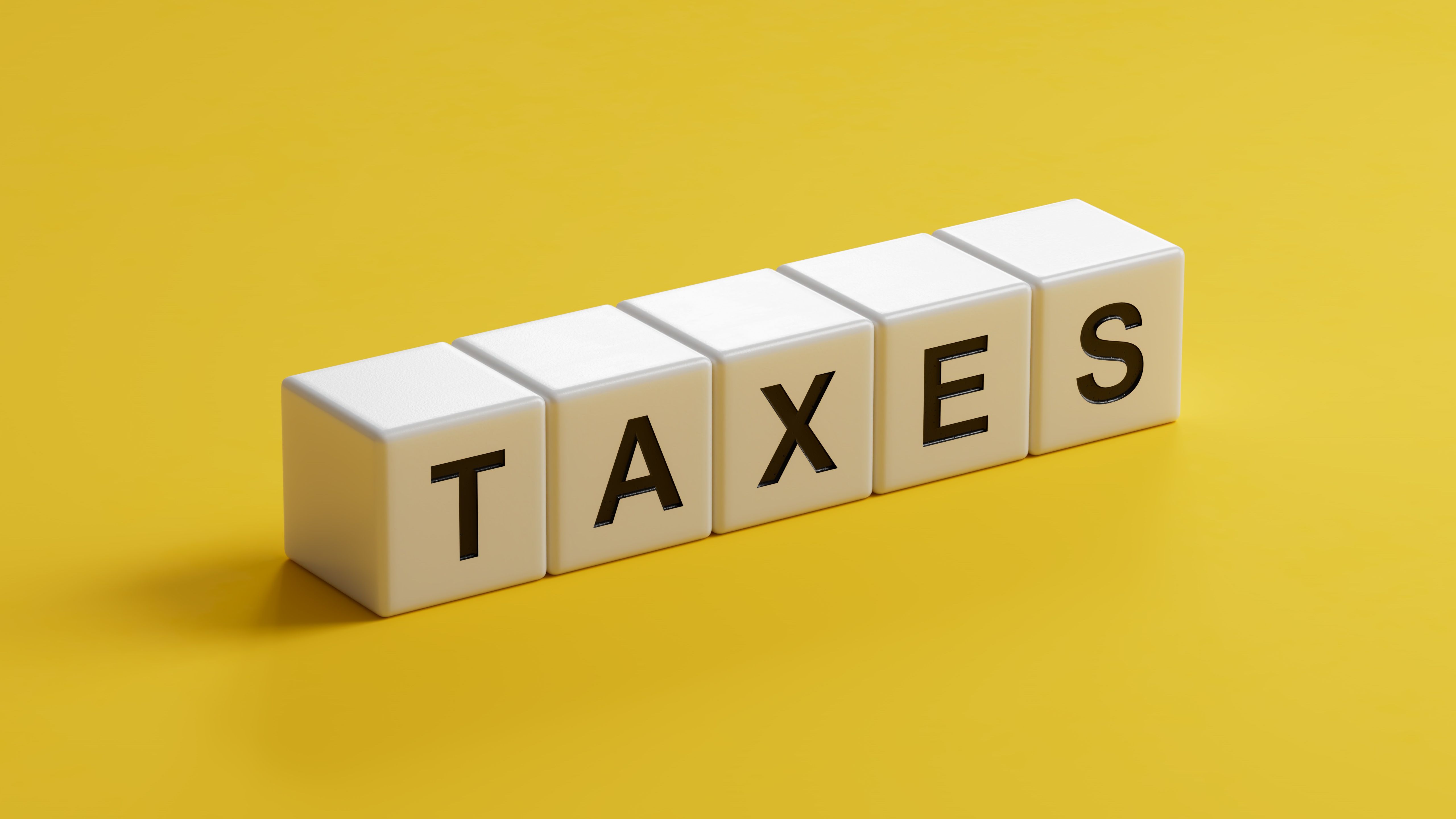 wooden cubes with TAXES business word.close up of wooden cubes,Business Concept.3D rendering on yellow background.