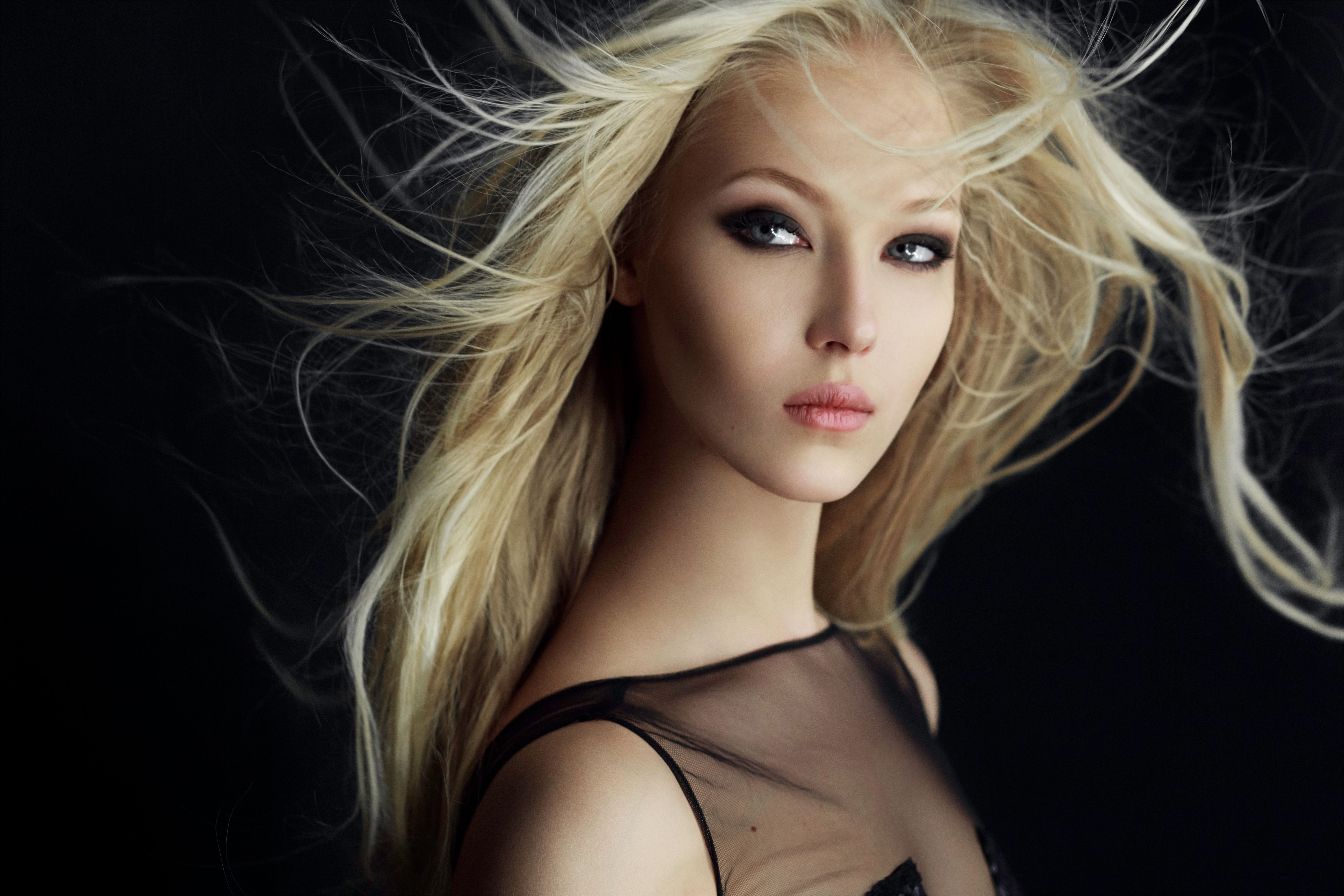 Graceful blonde girl in perfect make up with hair scattered by the wind, isolated on a black background. Graceful blonde girl in perfect make up with hair scattered by the wind, isolated on a black background.