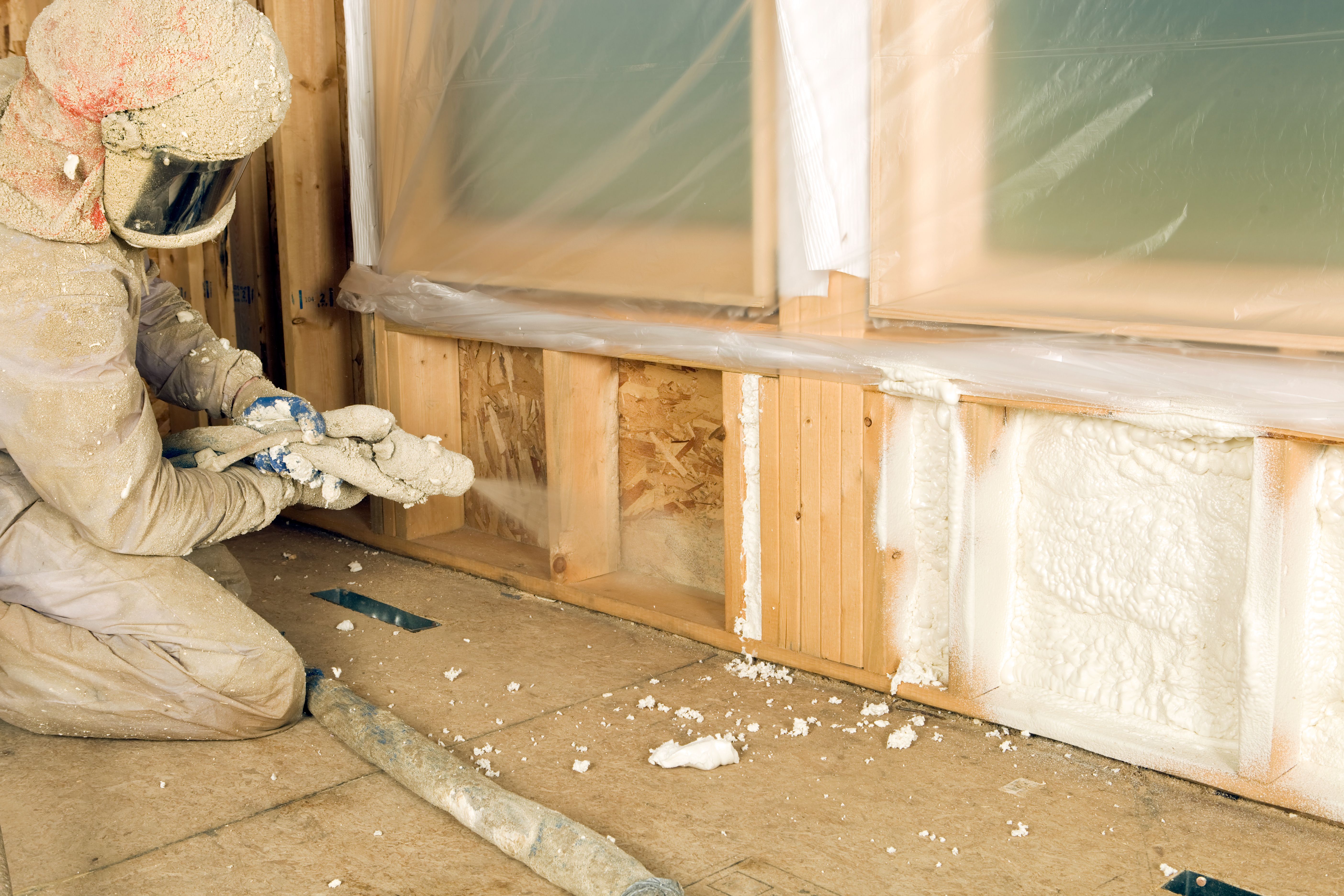 Construction Worker Spraying Expandable Foam Insulation between Wall Studs