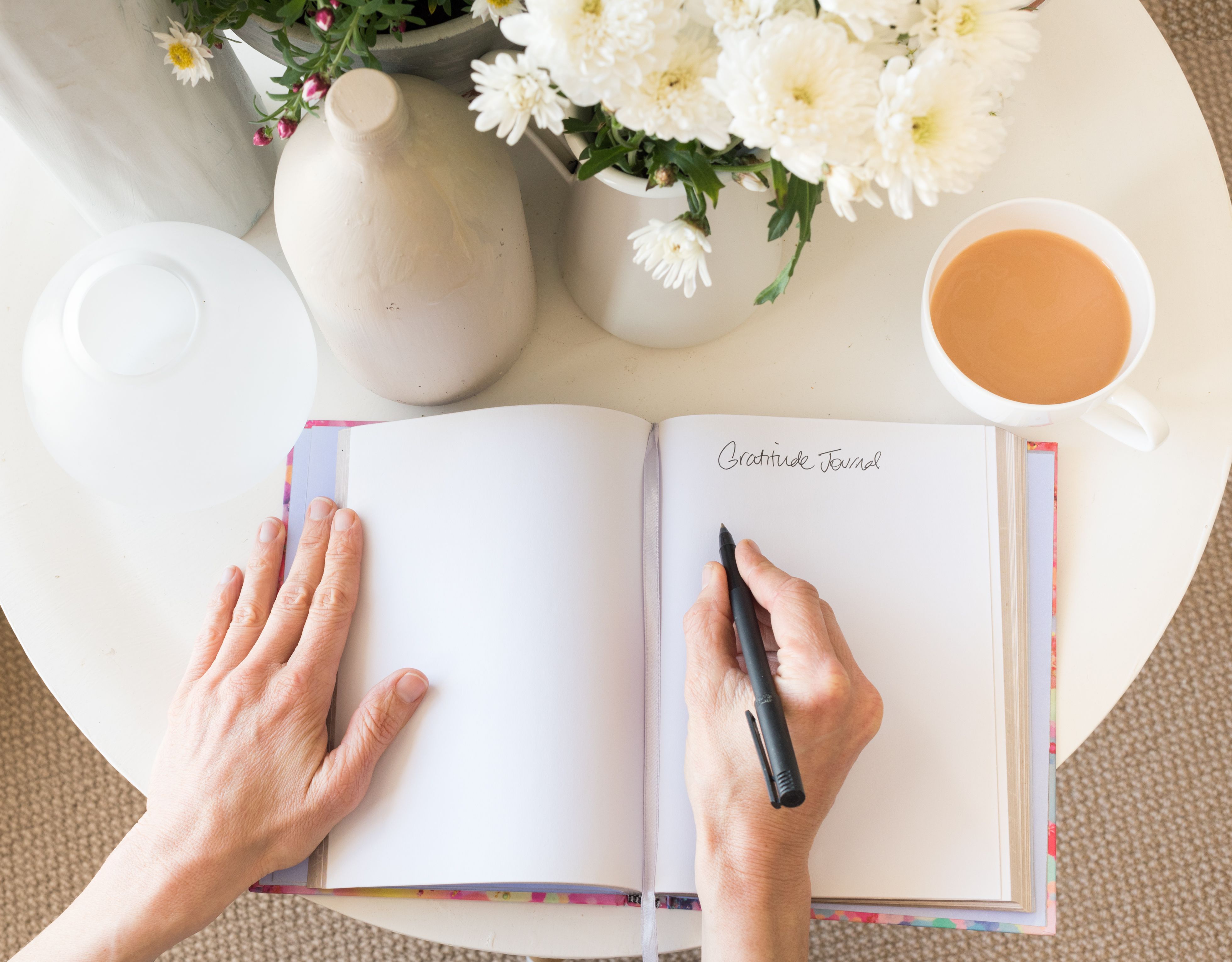 Cropped Hands Of Woman Writing In Diary By Coffee On Table At Home Cropped Hands Of Woman Writing In Diary By Coffee On Table At Home