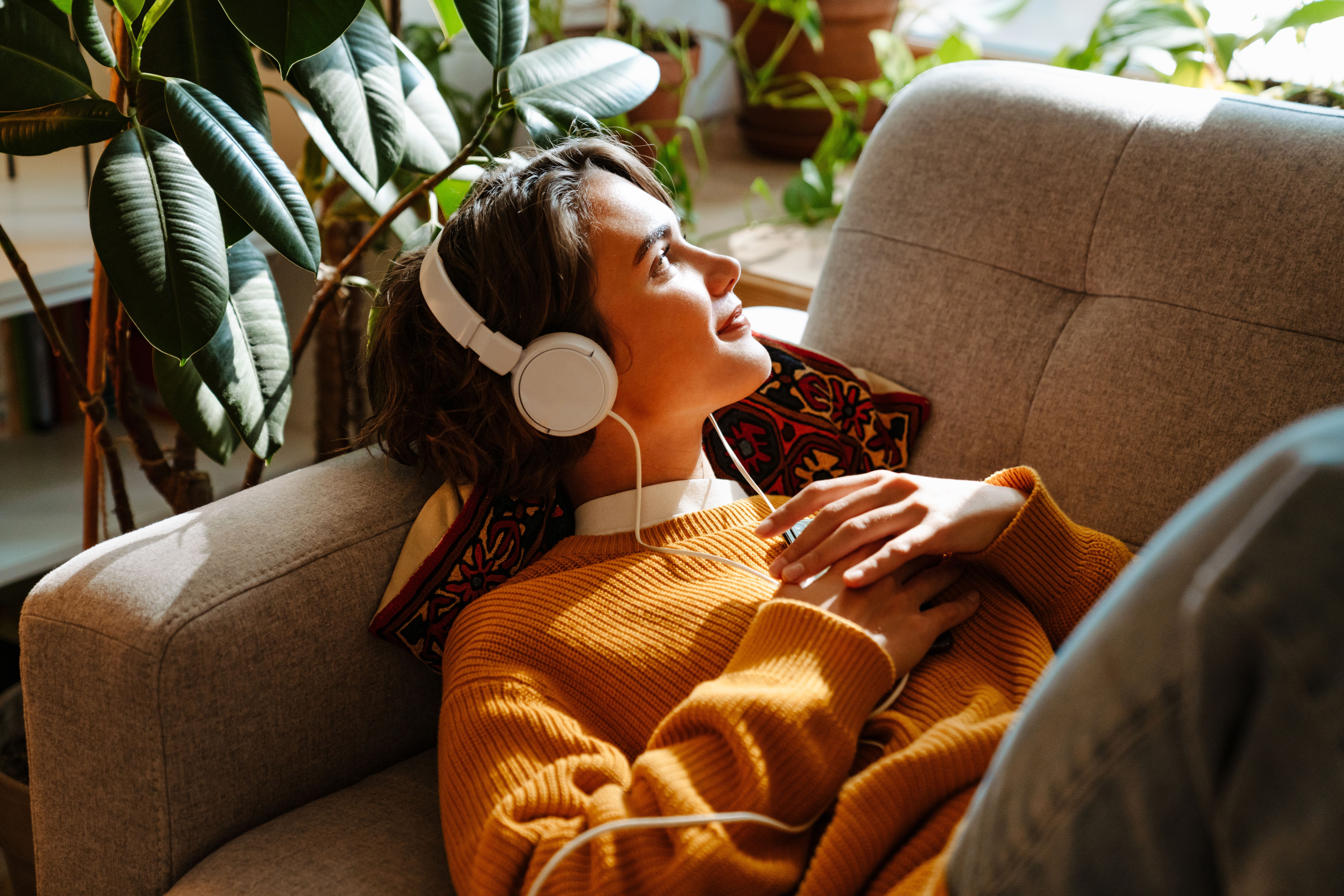 Brunette young woman listening music while resting on couch Brunette young woman listening music while resting on couch
