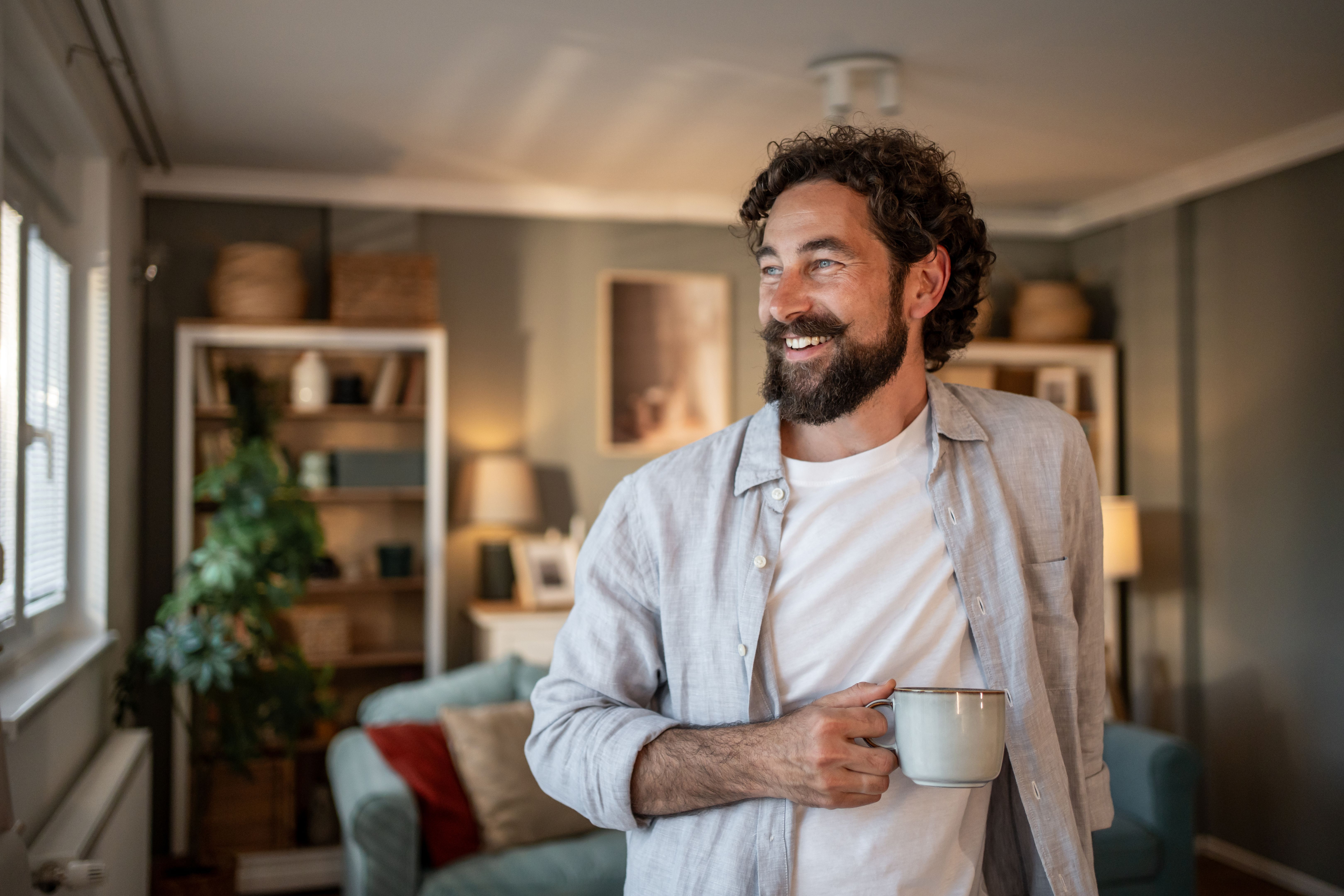 Smiling bearded man drinking coffee and enjoying domestic life