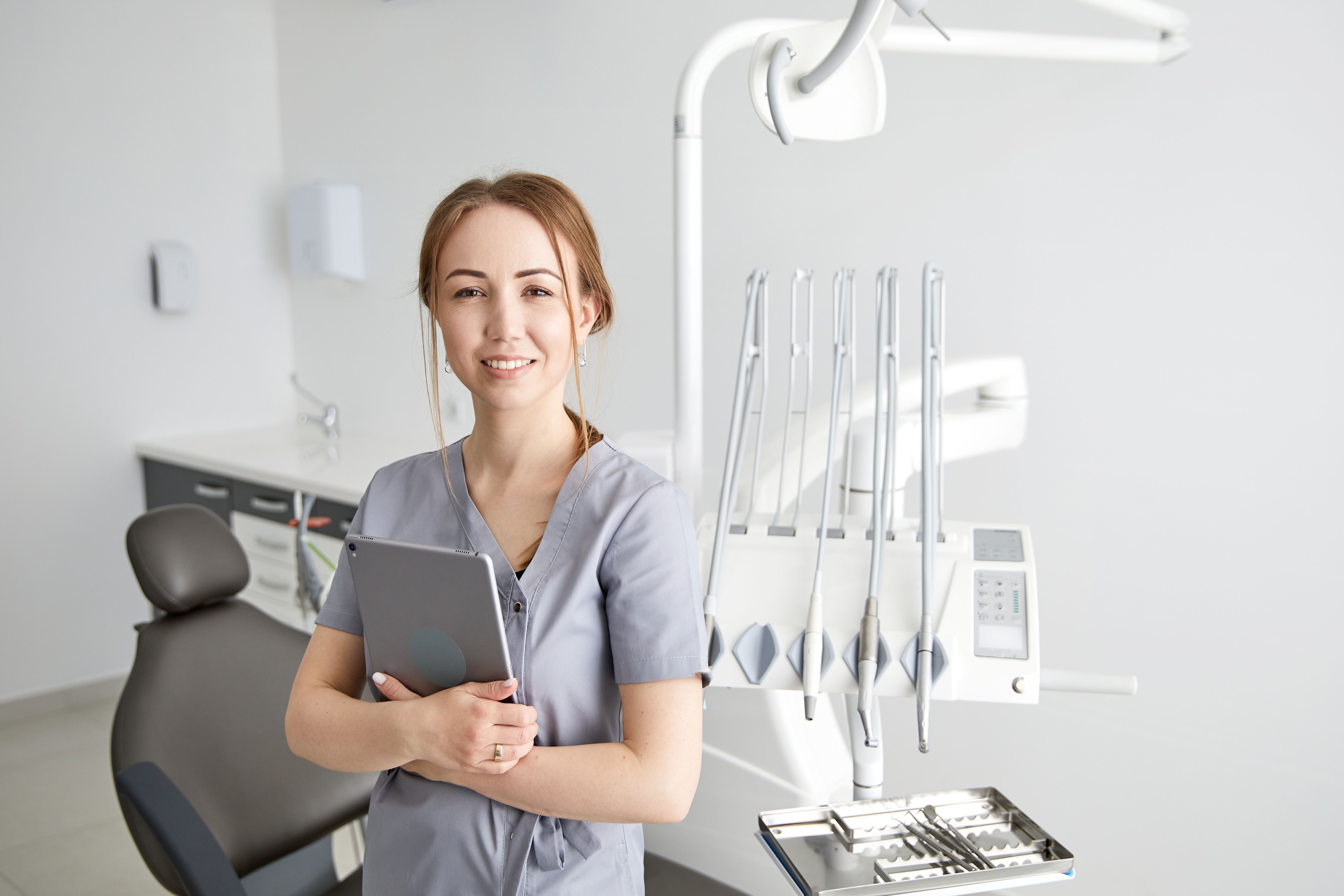 Young doctor in a dental clinic. Portrait of young female doctor dentist with digital tablet in dental office Young doctor in a dental clinic. Portrait of young female doctor dentist with digital tablet in dental office