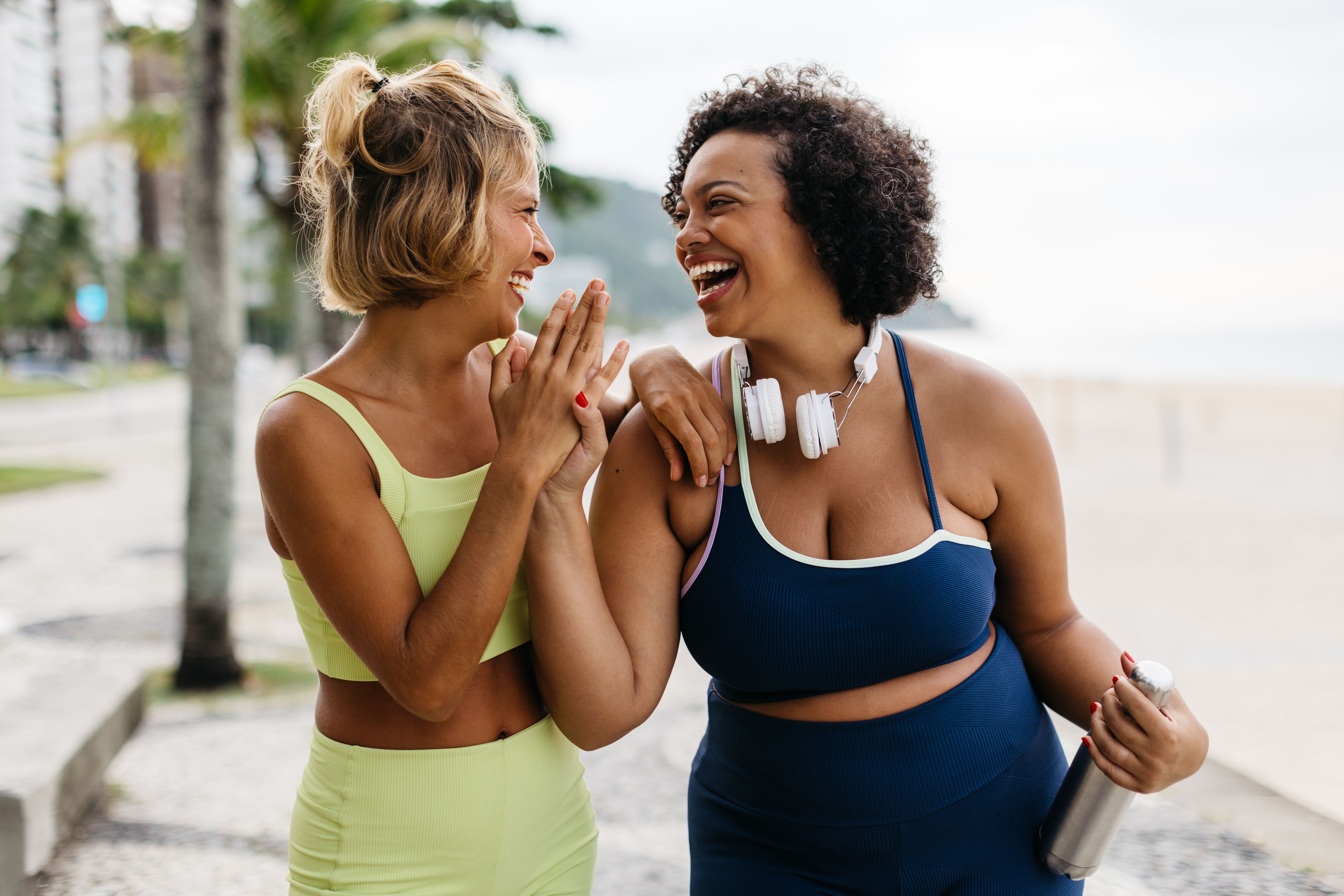 Fitness women laughing and high-fiving after a beach workout Fitness women laughing and high-fiving after a beach workout