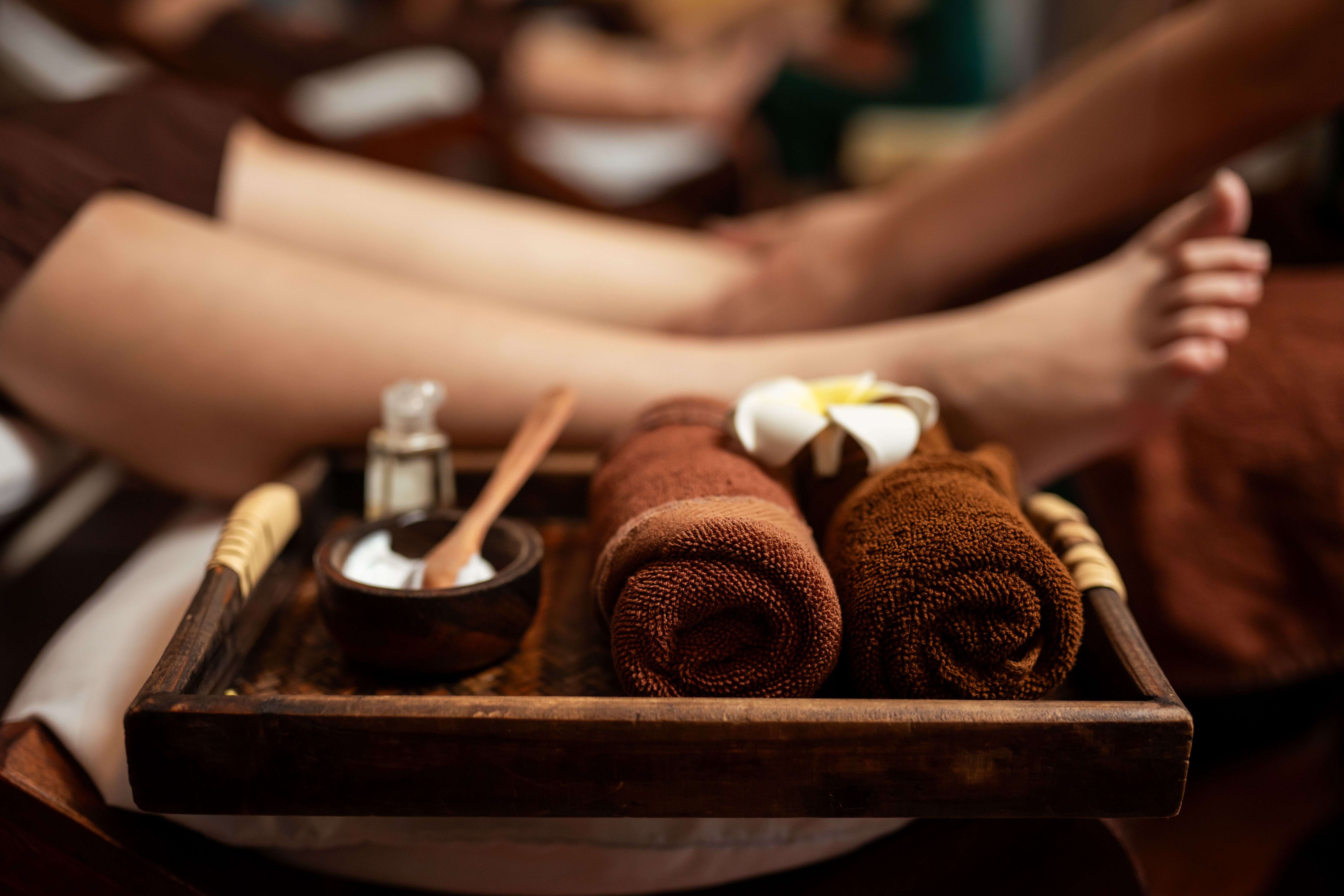 Spa treatment foot massage set with blurred masseuse service foot massage customer on background.