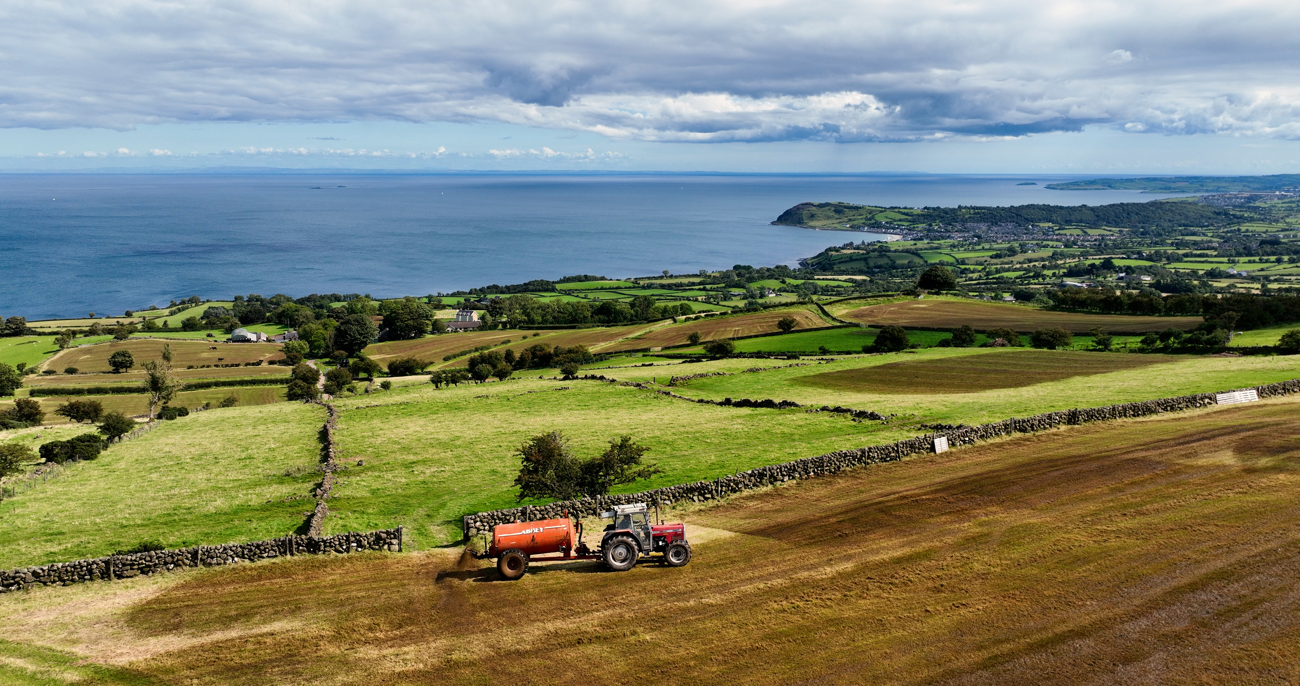 Aerial Photo of Massey Ferguson 390T Tractor and Abbey Tanker spreading manure slurry in a field on farm in UK 09-09-23 Aerial Photo of Massey Ferguson 390T Tractor and Abbey Tanker spreading manure slurry in a field on farm in UK 09-09-23