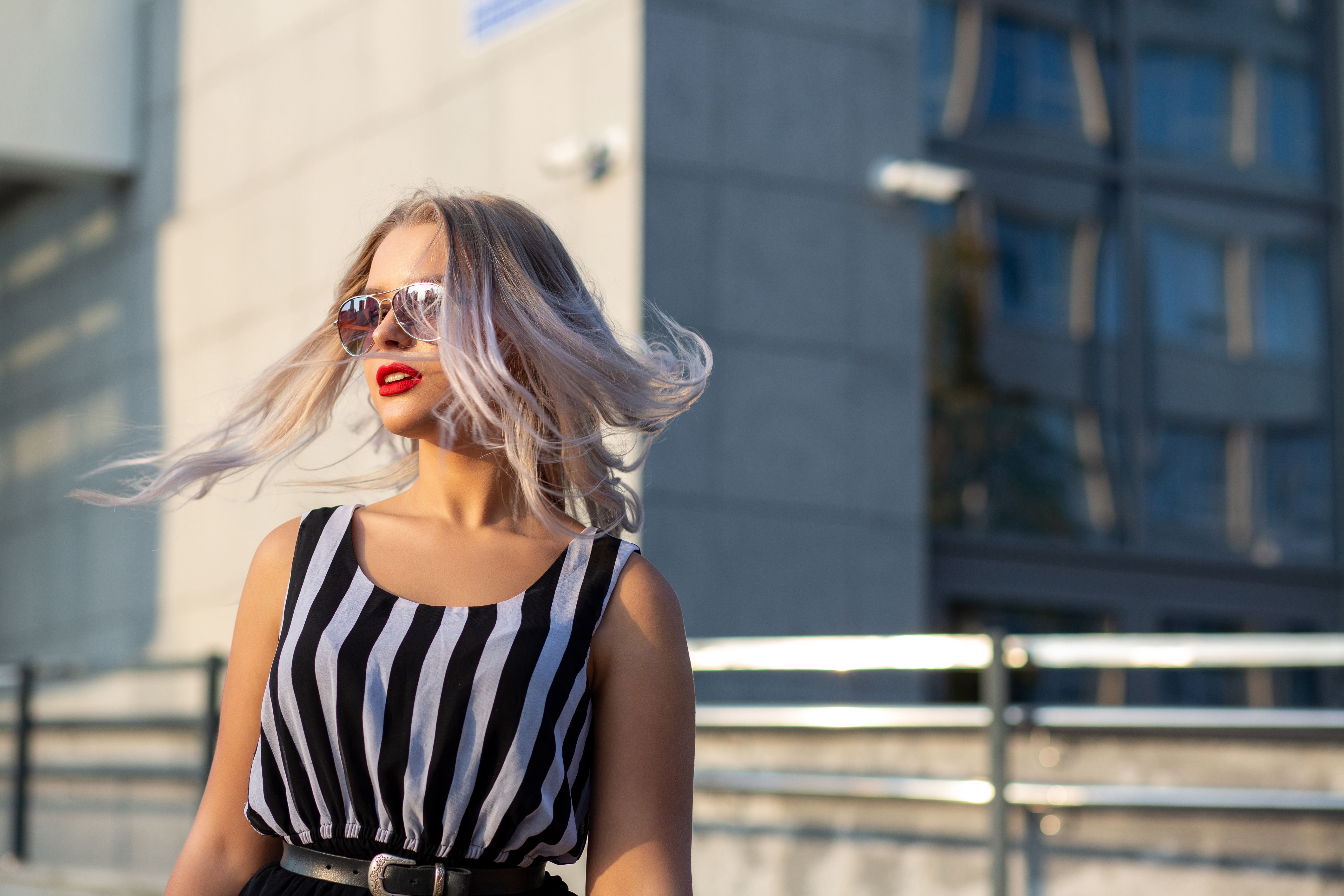 Adorable blonde model wearing glasses, posing with fluttering hair at the city. Space for text Adorable blonde model wearing glasses, posing with fluttering hair at the city. Space for text